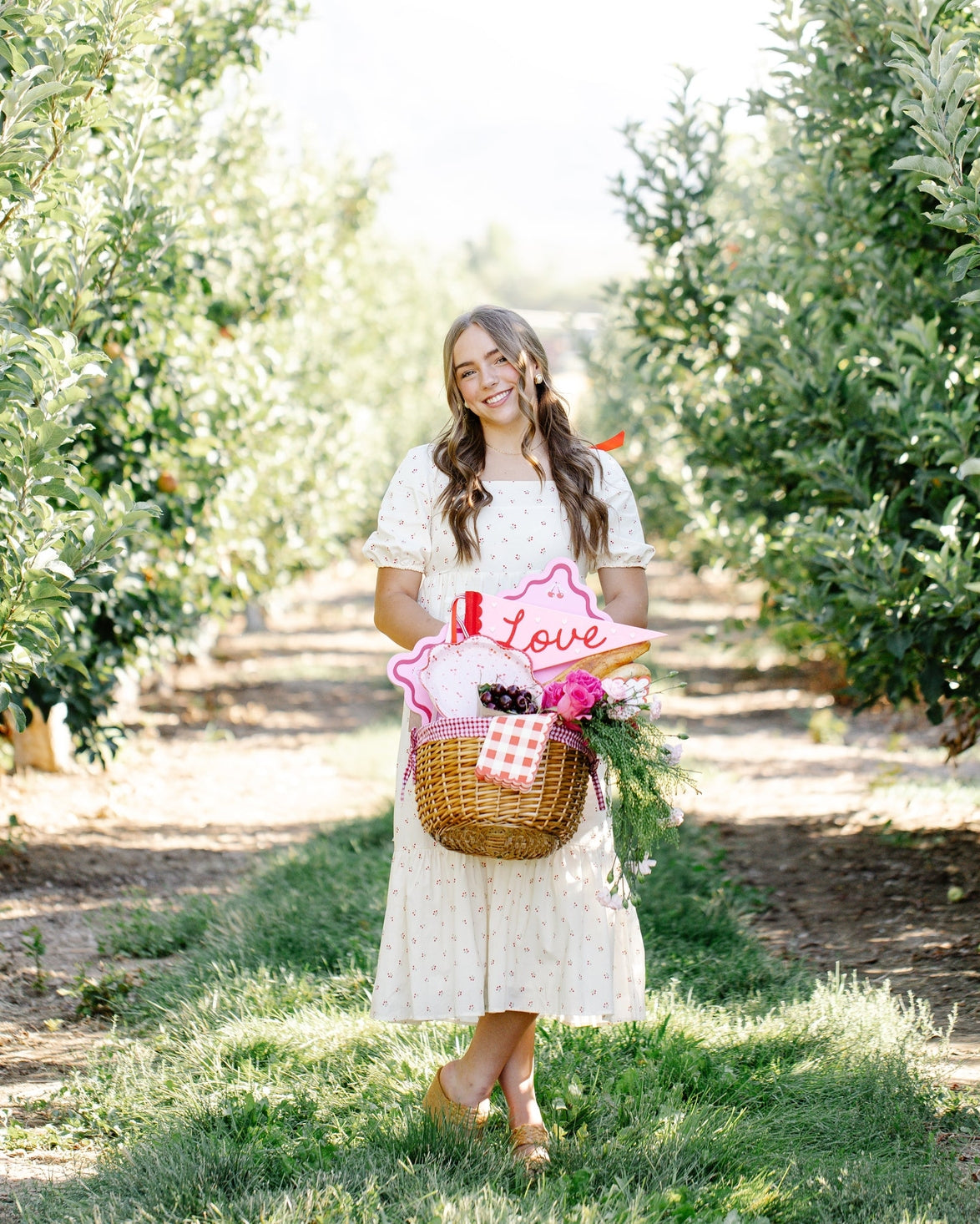 Woman in an apple orchard holding a basket with flowers and a &