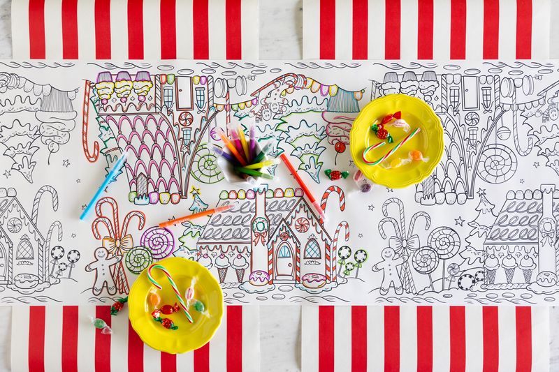 Coloring tablecloth with gingerbread house designs and candy decorations on a striped tablecloth.