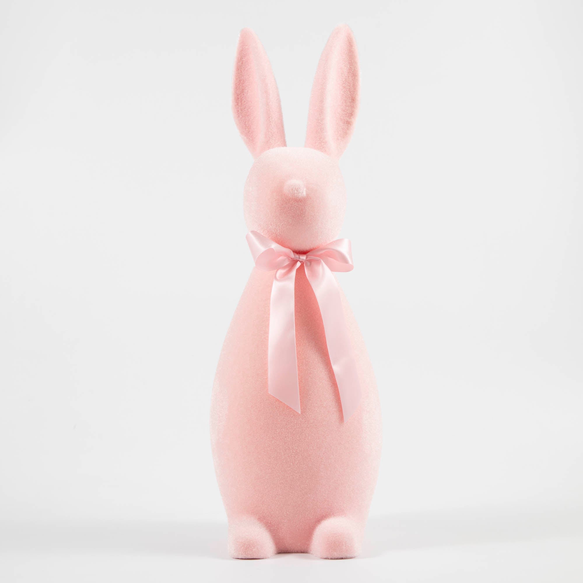 Pink flocked bunny with a pink bow tied around its neck.