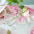 A pink and white table setting with a Qualia Mouth Blown Clear Vase - Exclusively at Hester & Cook of favorite flowers.