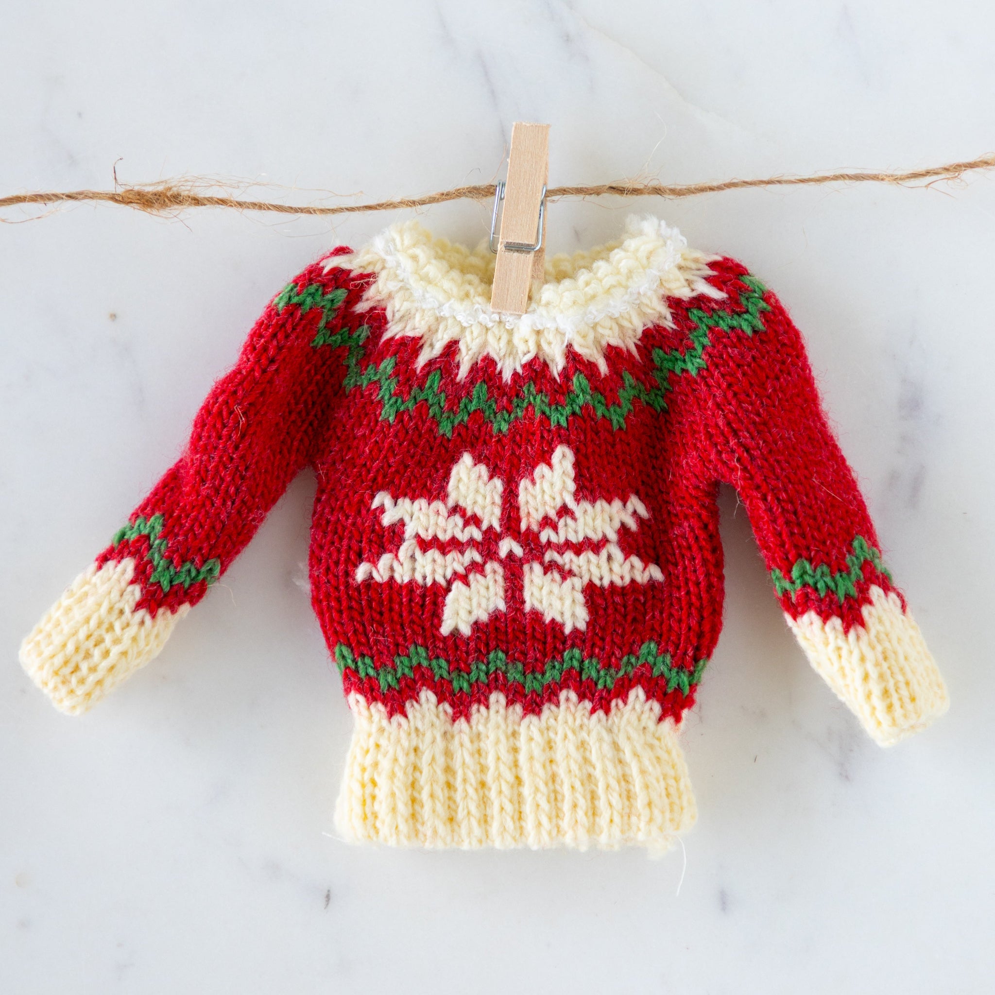 Knitted sweater with a snowflake design hanging on a clothesline.