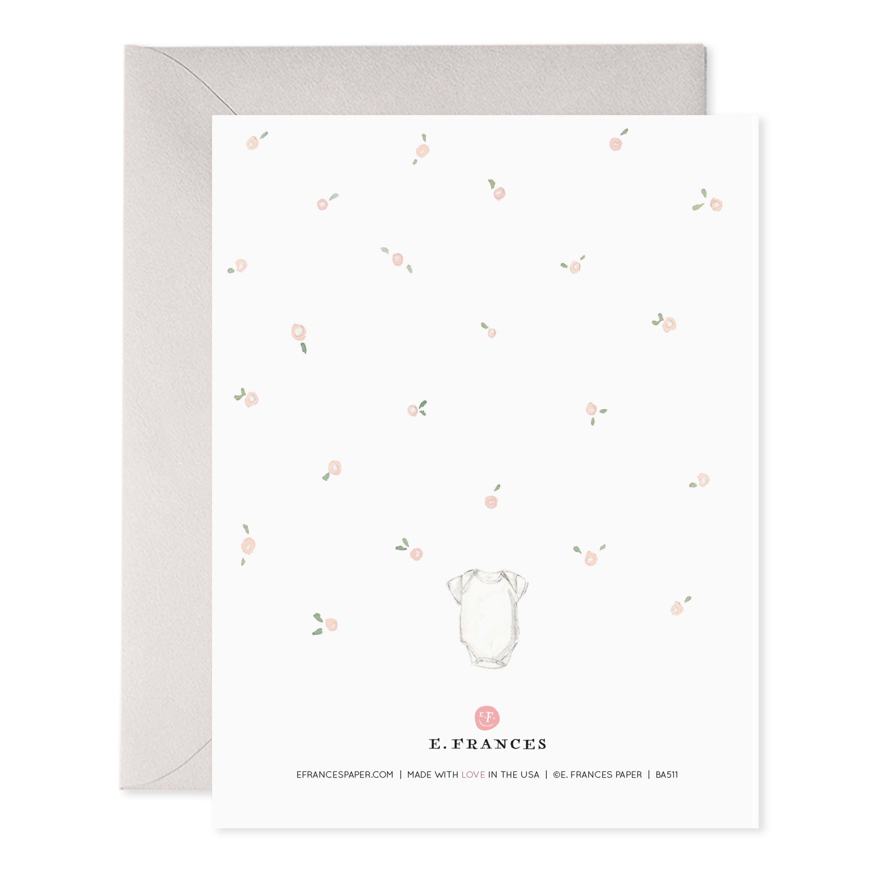 Back of card with pink flowers and small white onesie.
