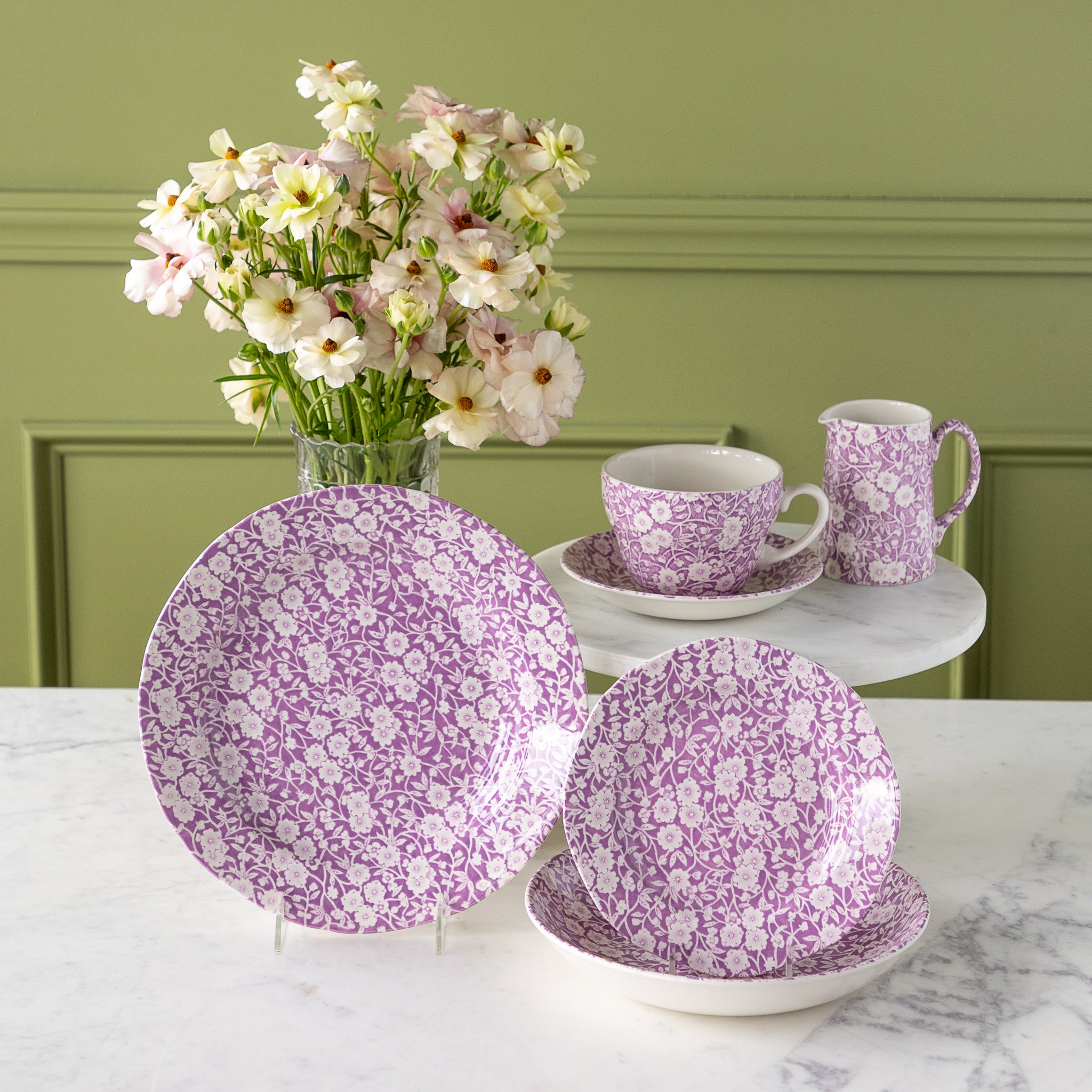 Burleigh Blossom Calico dinnerware propped with a vase of flowers behind it.