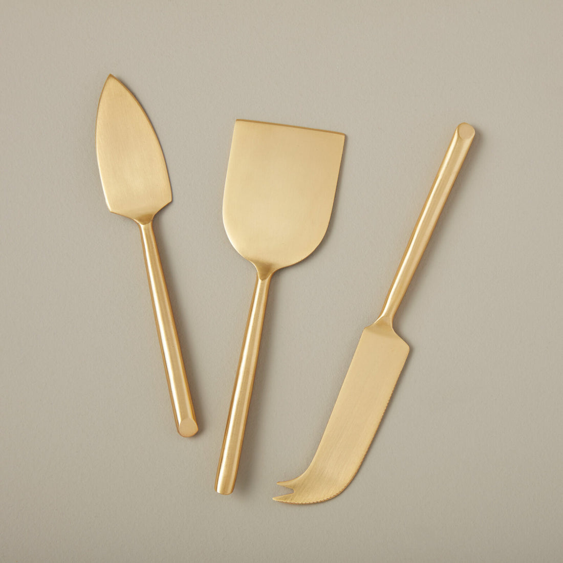 Three Matte Gold Cheese Spreaders Set of 3 by Be Home arranged neatly on a light background.