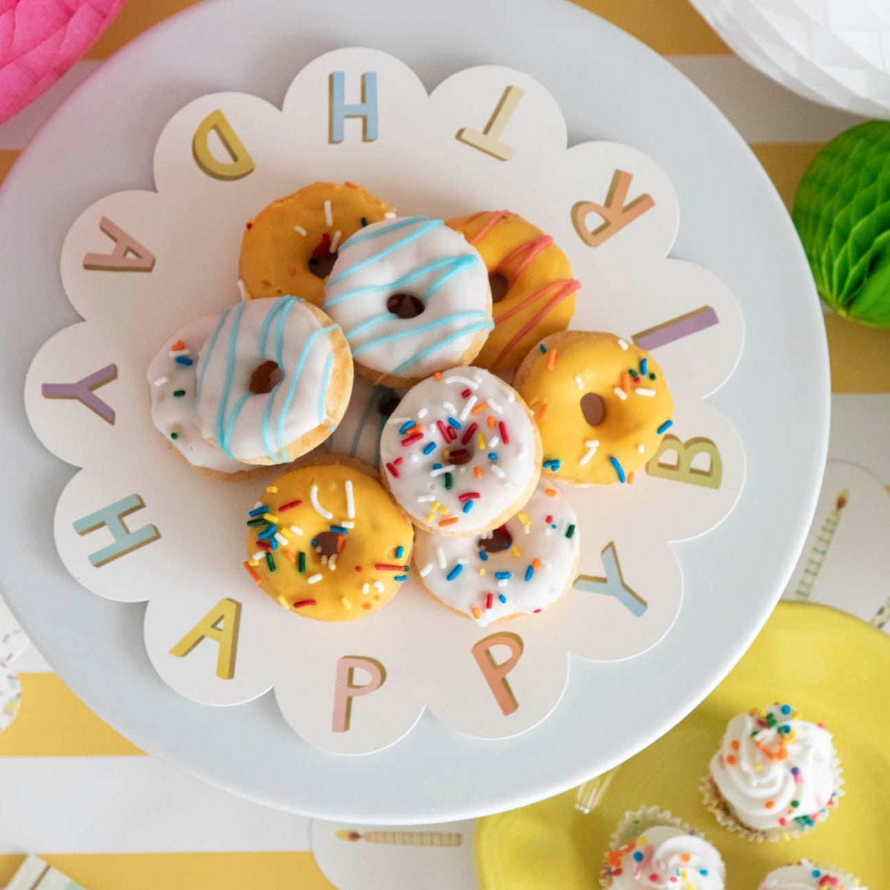 A plate of treats on a Happy Birthday Serving Paper from Hester & Cook displayed on cake stands.