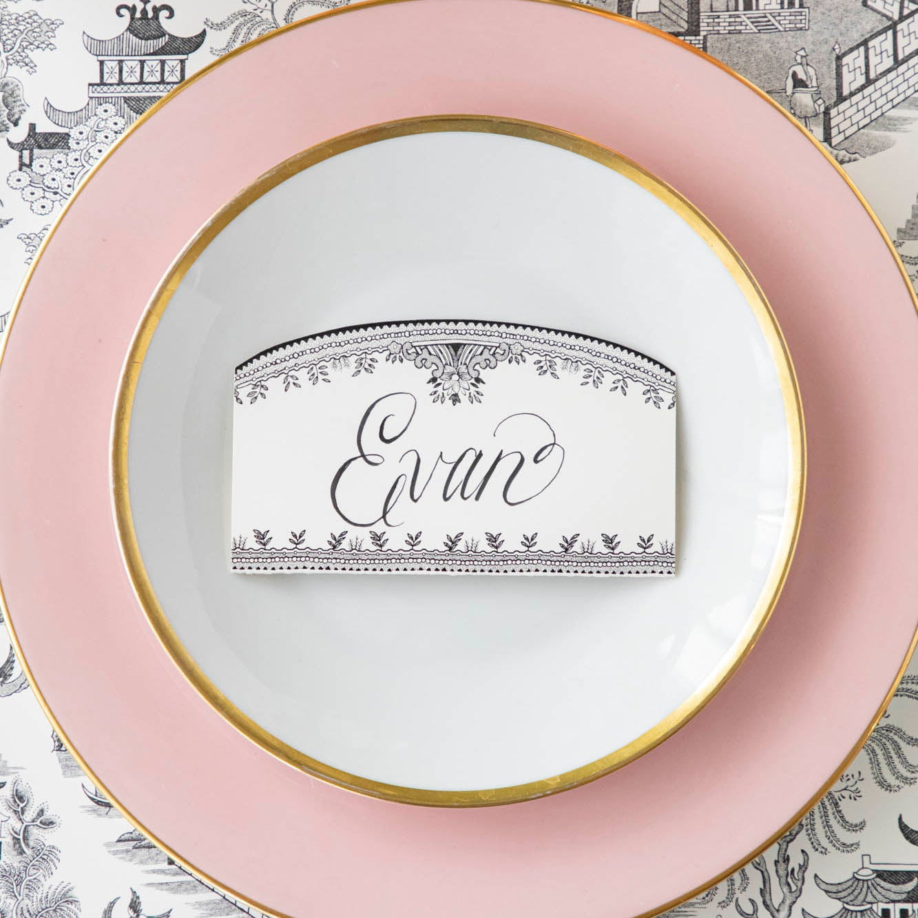 Black Willow Place Card with "Evan" written on it, resting on dinner plates on an elegant place setting.