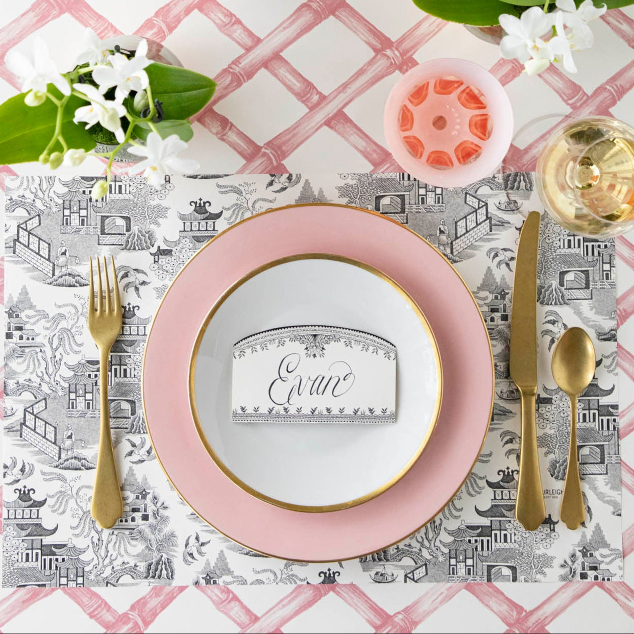 Black Willow Place Card with "Evan" written on it, resting on dinner plates on an elegant place setting.