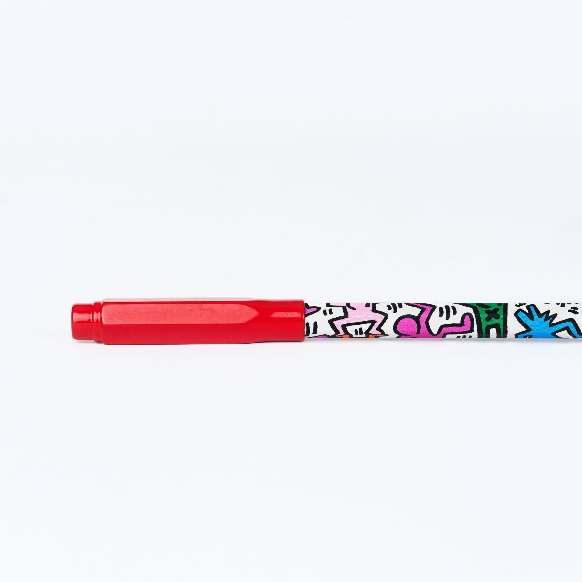 Blackwing pencil with Keith Haring artwork printed on it with a red pencil guard on the end.