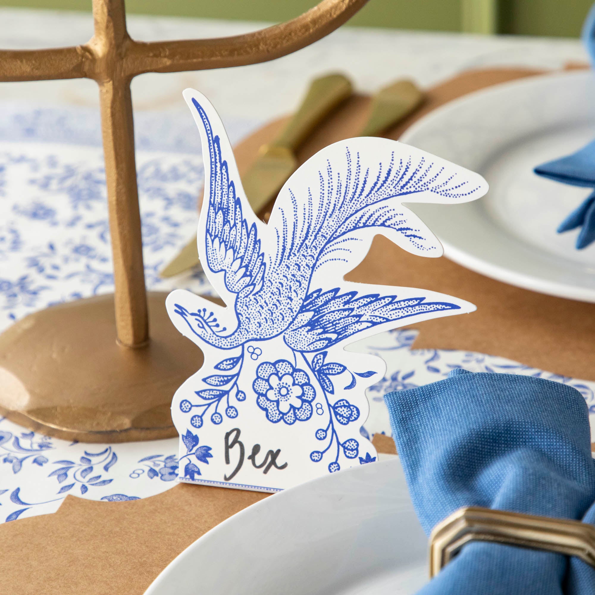 Blue Asiatic Pheasants Place Card with "Bex" written on it, behind an elegant place setting.