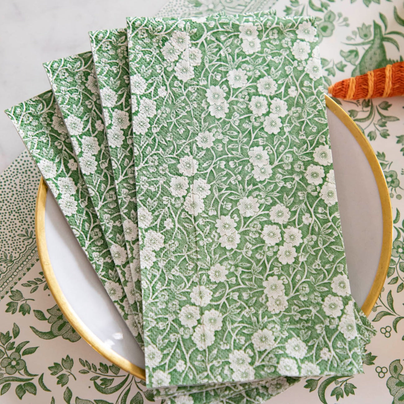 Four Green Calico Guest Napkins fanned out on a plate in an elegant table setting.