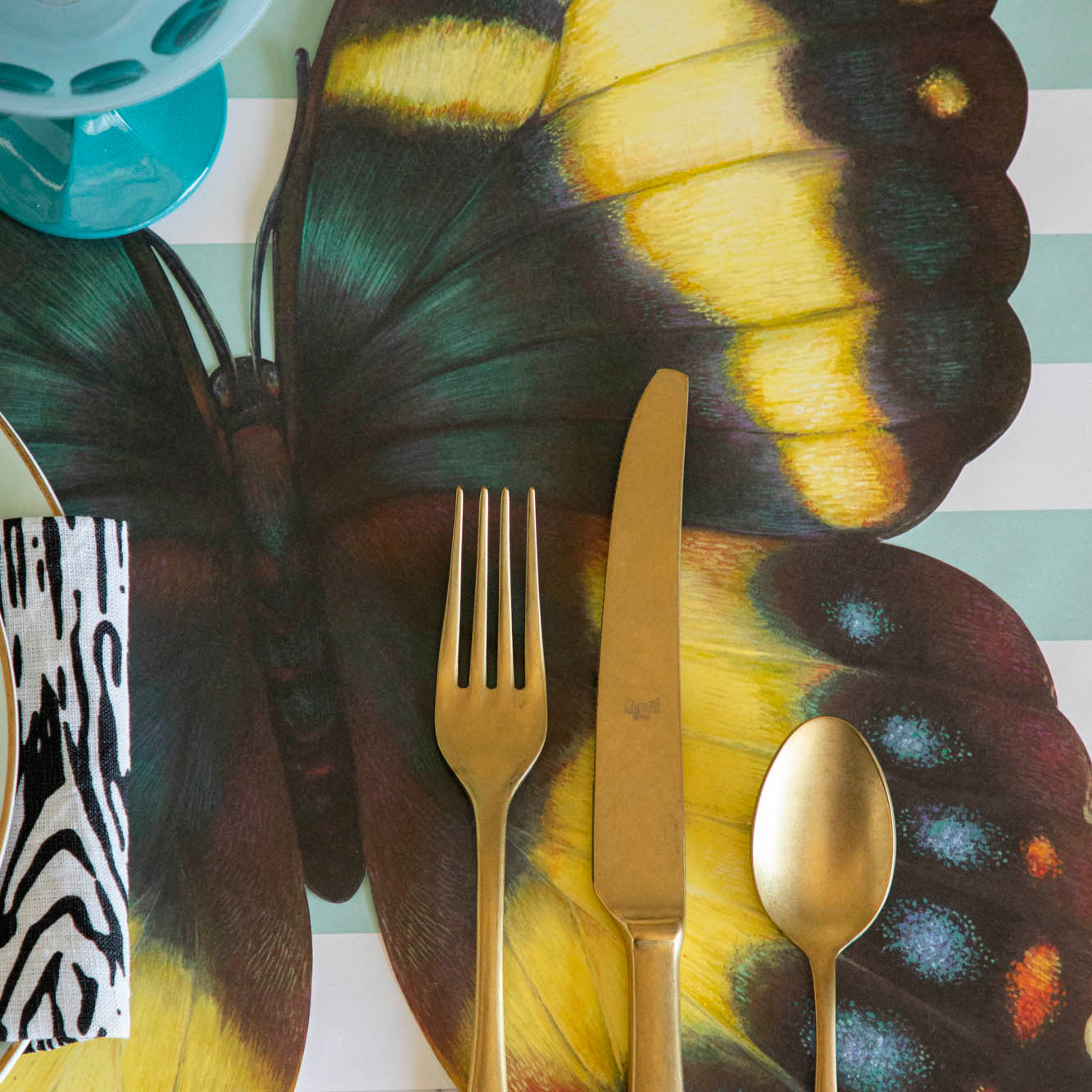 Close-up of a set of gold flatware on a Die-cut Butterfly Placemat.