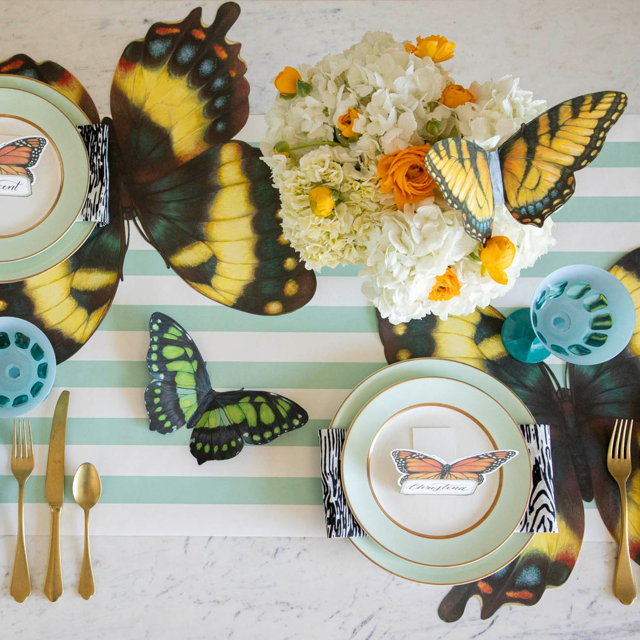 Top-down view of an elegant butterfly-themed tablescape featuring Monarch Butterfly Place Cards standing on each plate.