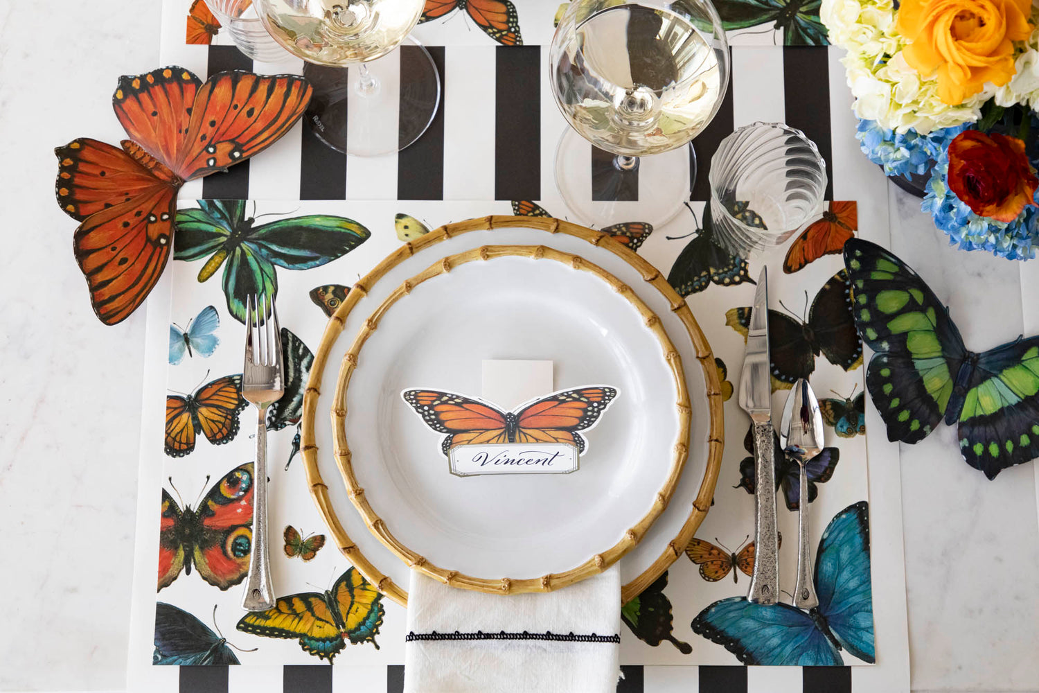 Top-down view of an elegant place setting, with the orange and green Butterfly Table Accents resting on either side of the placemat.