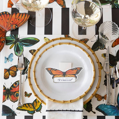 Top-down view of an elegant butterfly-themed place setting featuring a Monarch Butterfly Place Card labeled &quot;Vincent&quot; standing on the plate.