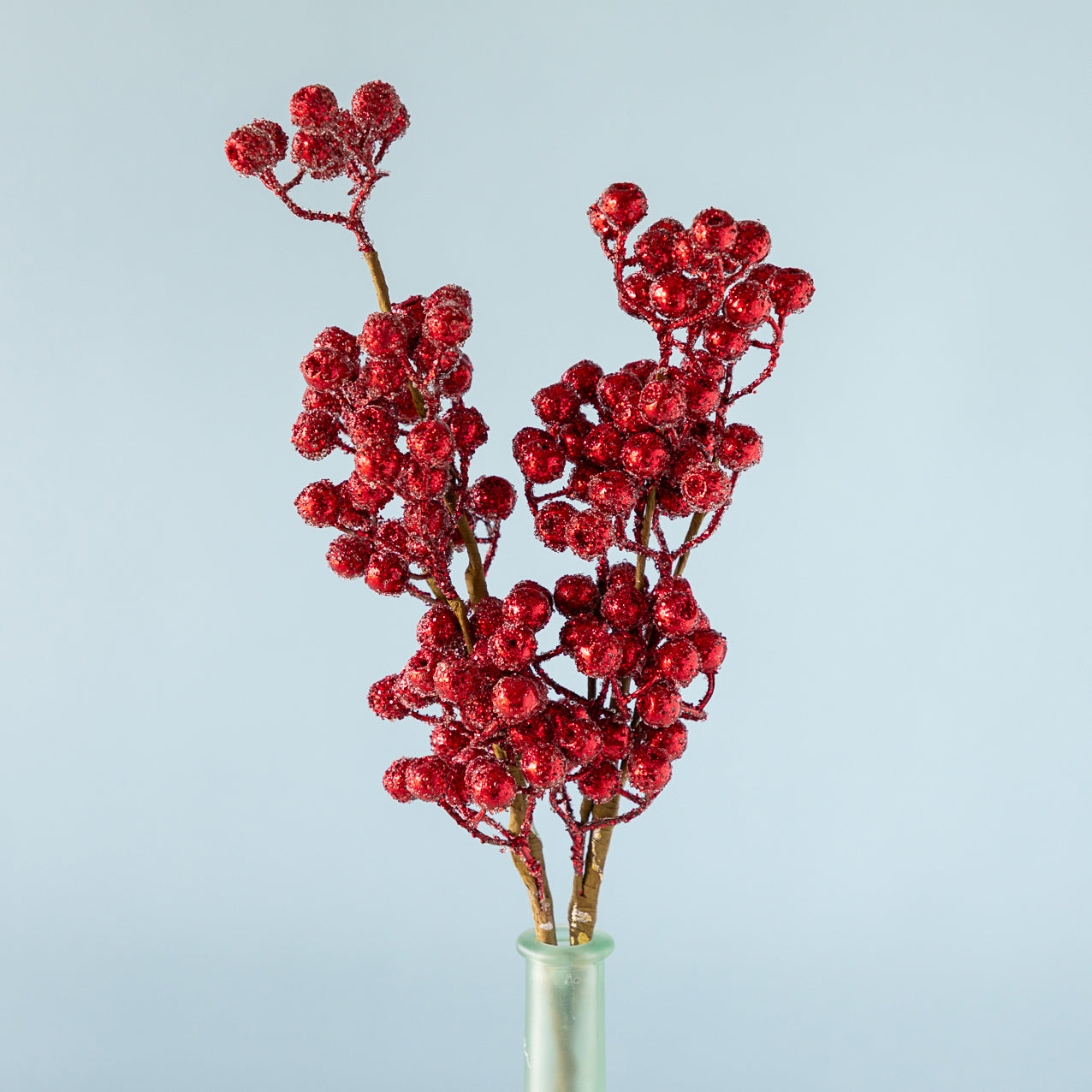 Cranberry Red Iced Picks in a green bottle, against a light blue background.