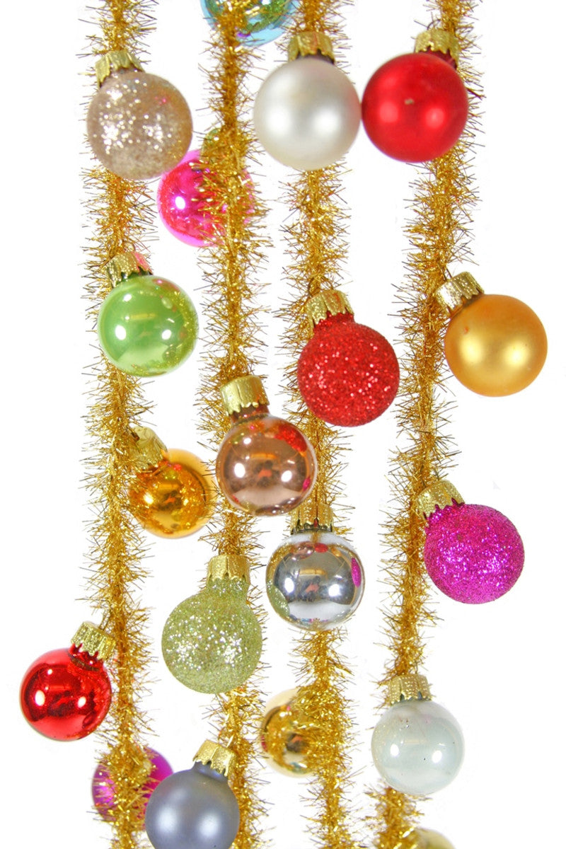 A garland made with gold tinsel string with multi colored balls attached to it.
