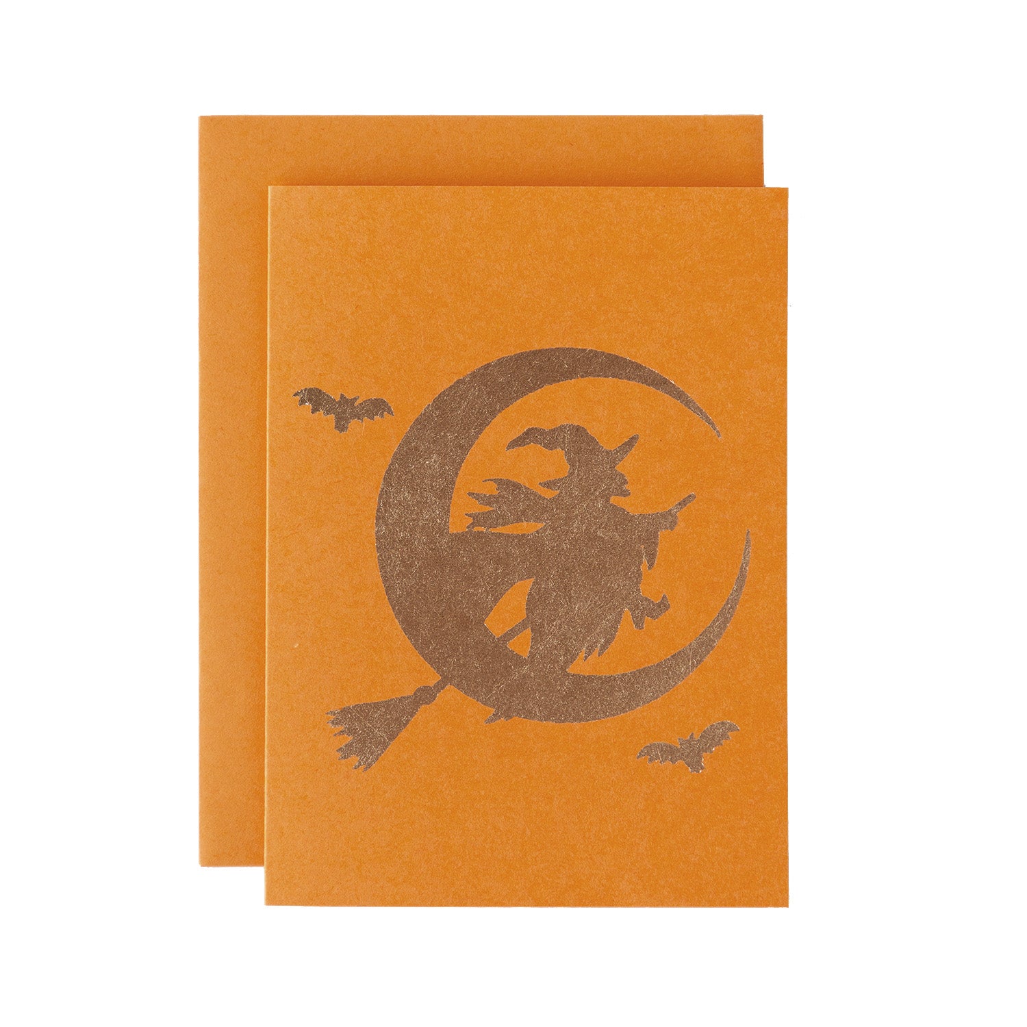 A gold foiled wicked witch riding on a broom, in front of a crescent moon with two flying bats, against an orange background with a matching envelope.