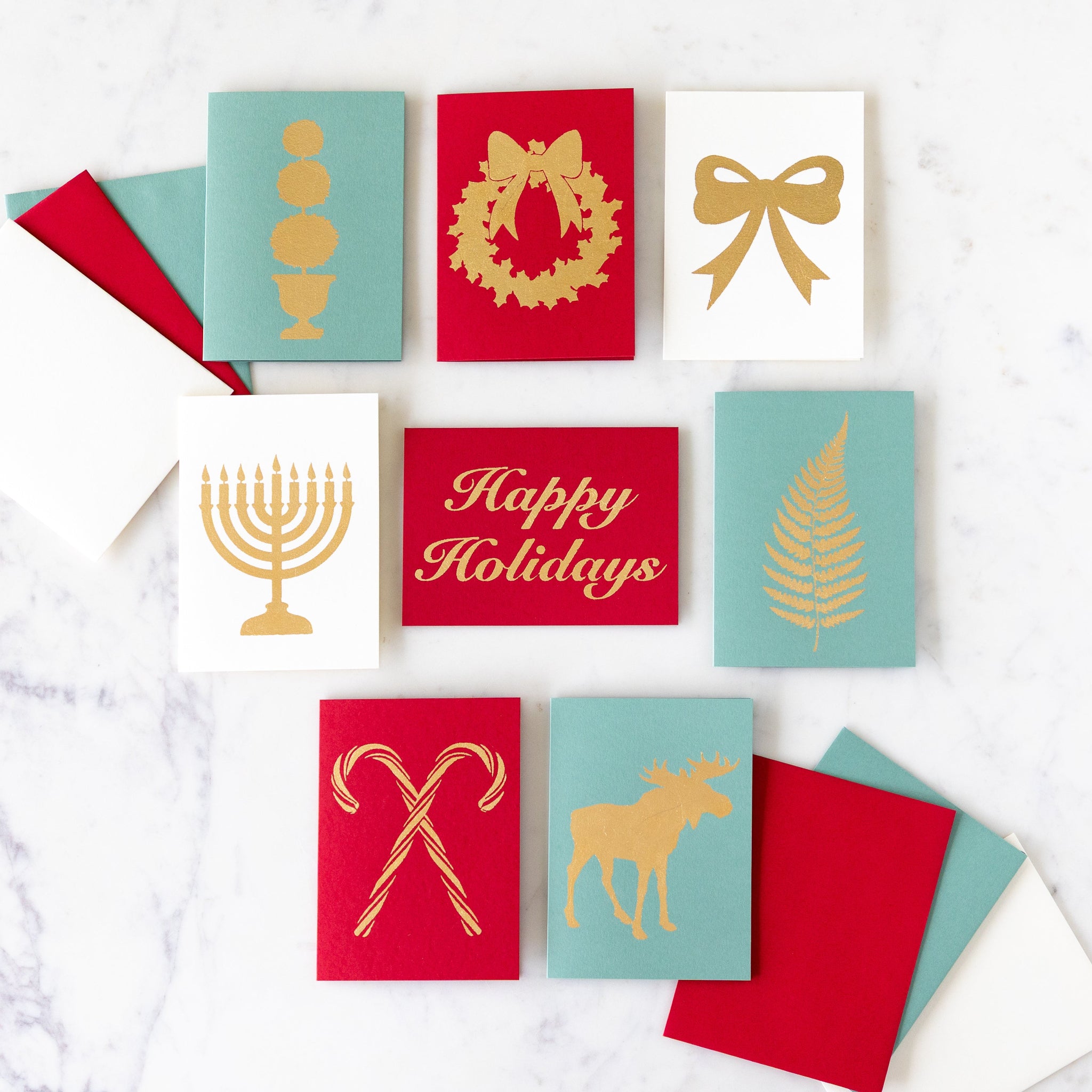 An assortment of Catherine Greenup holiday cards, arranged on a marble table.