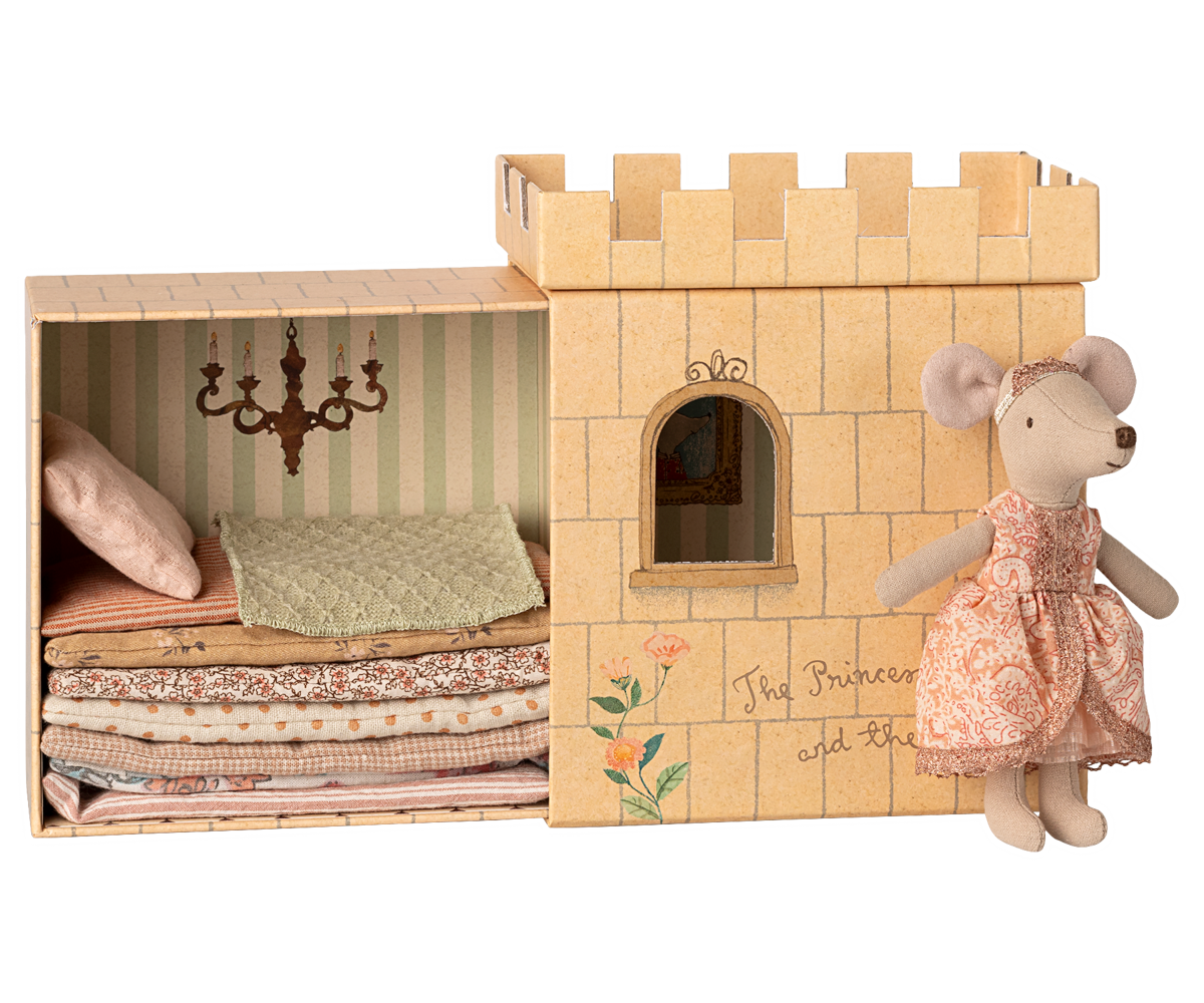 Castle toy with bedding and a mouse doll in a dress on a white background.