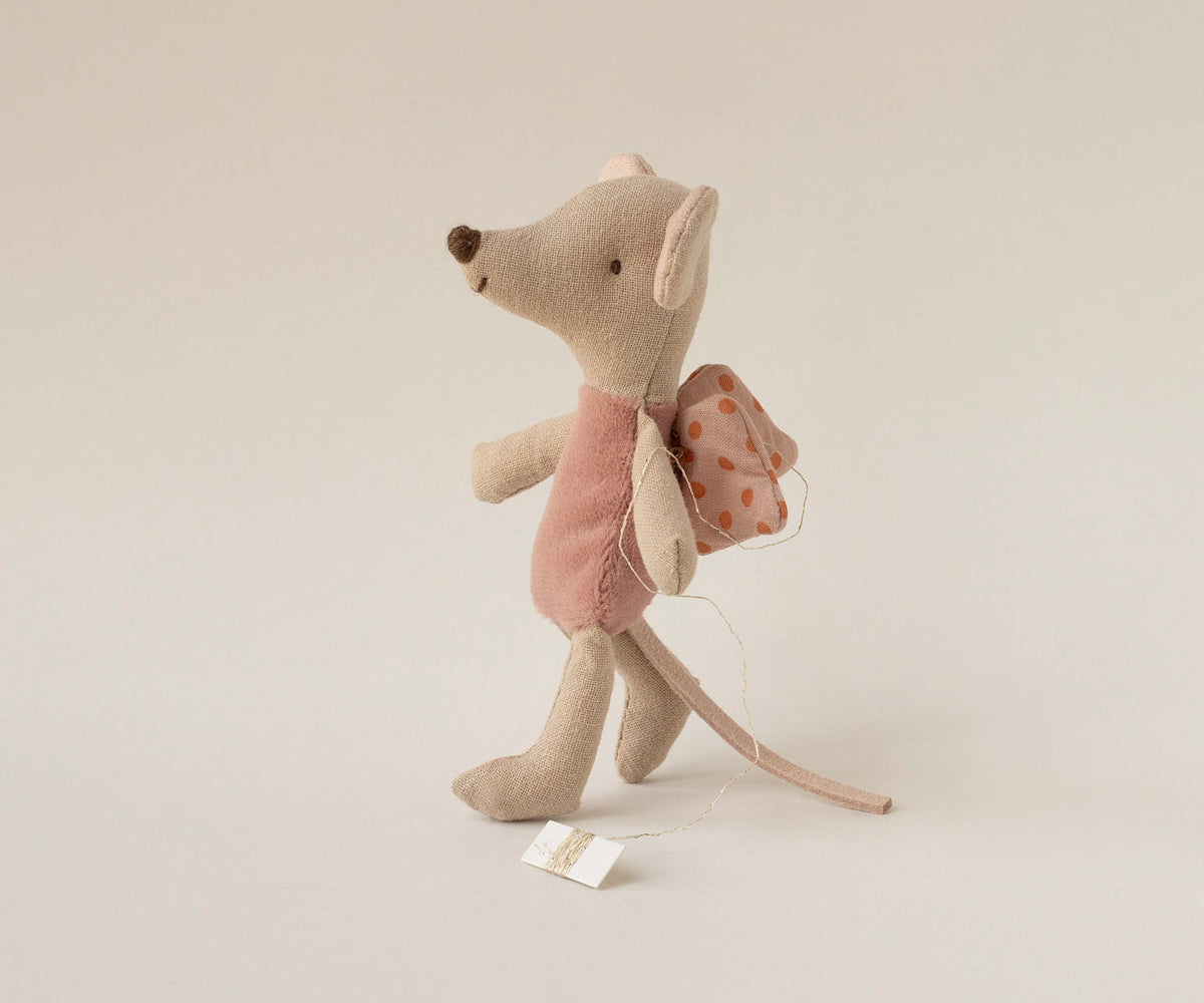 Stuffed mouse toy with a pink dress and backpack on a beige background.