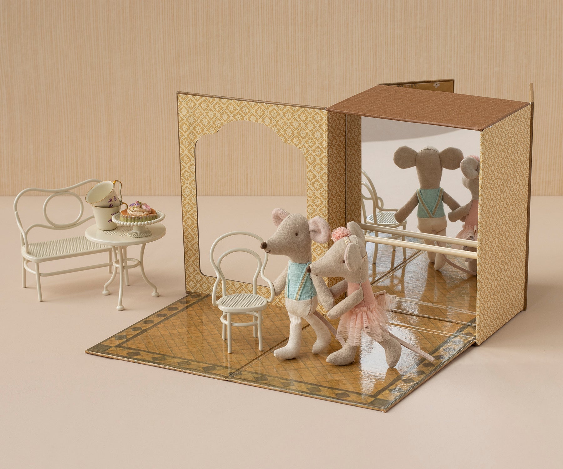 Toy mouse figures in a decorative box with a miniature table and chairs.