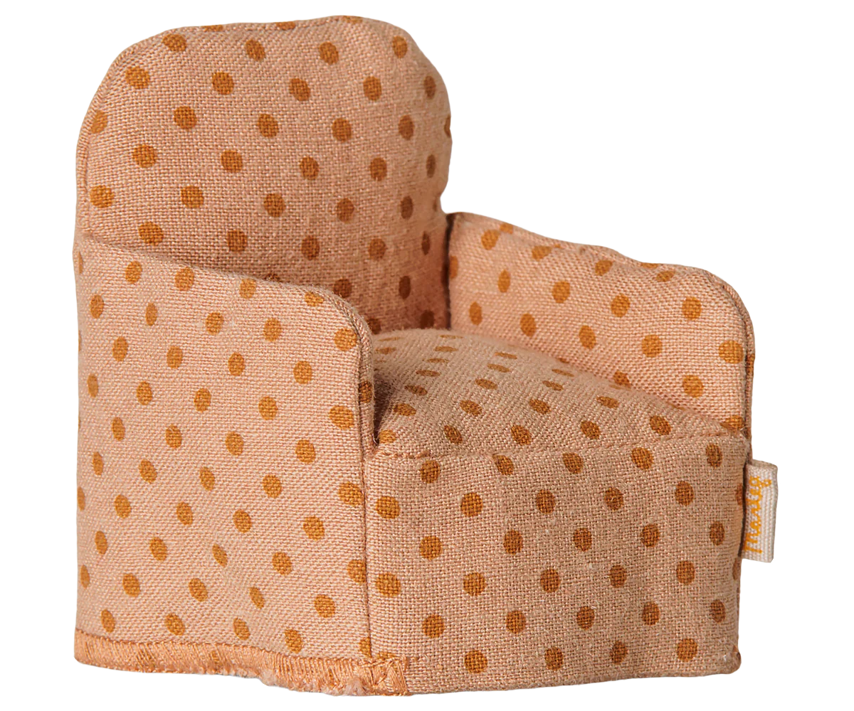 A small fabric armchair with a warm beige base and brown polka dots, photographed on a plain white background. A small fabric brand tag is visible on the right side.