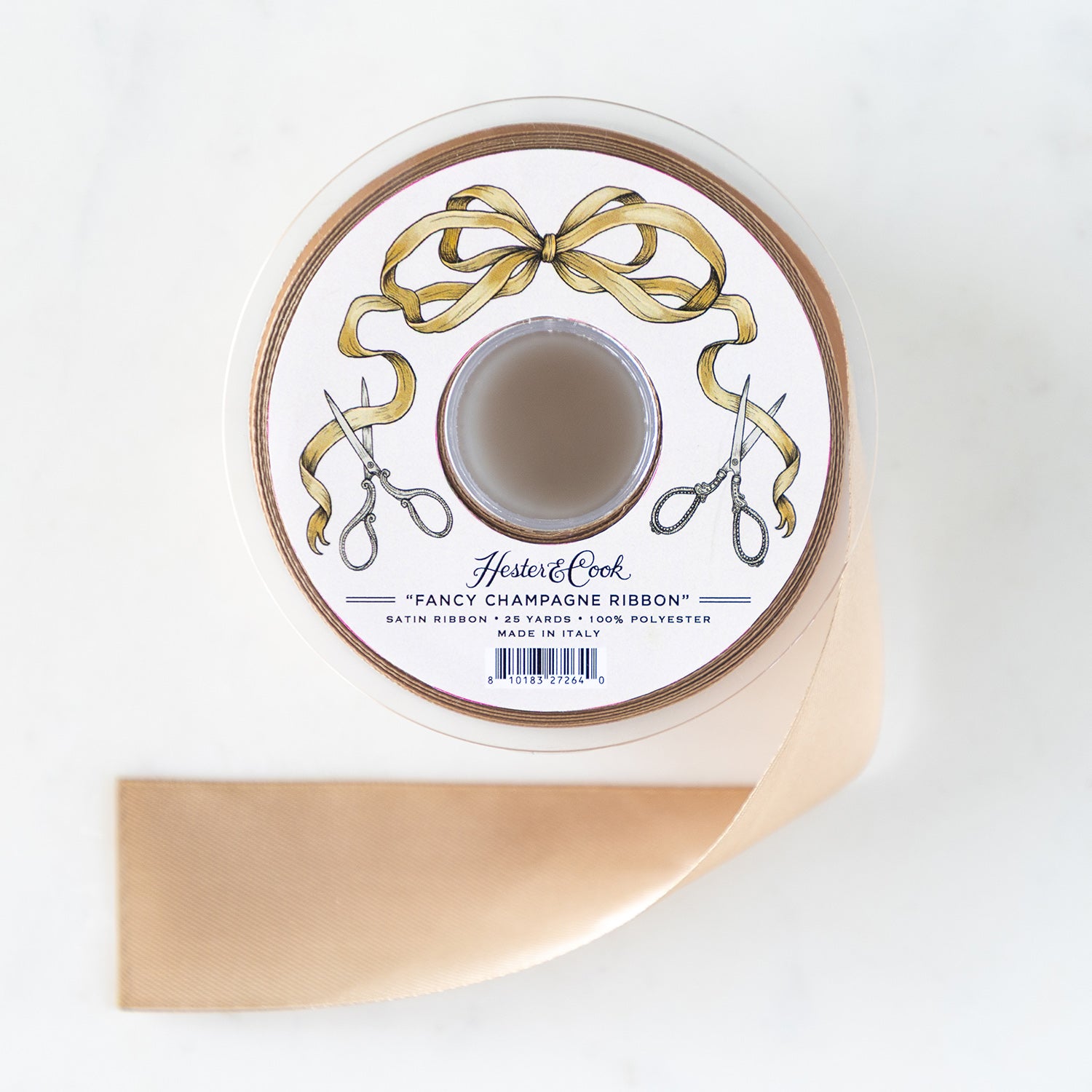 A spool of champagne satin ribbon with a label featuring illustrated scissors and Champagne Ribbon.