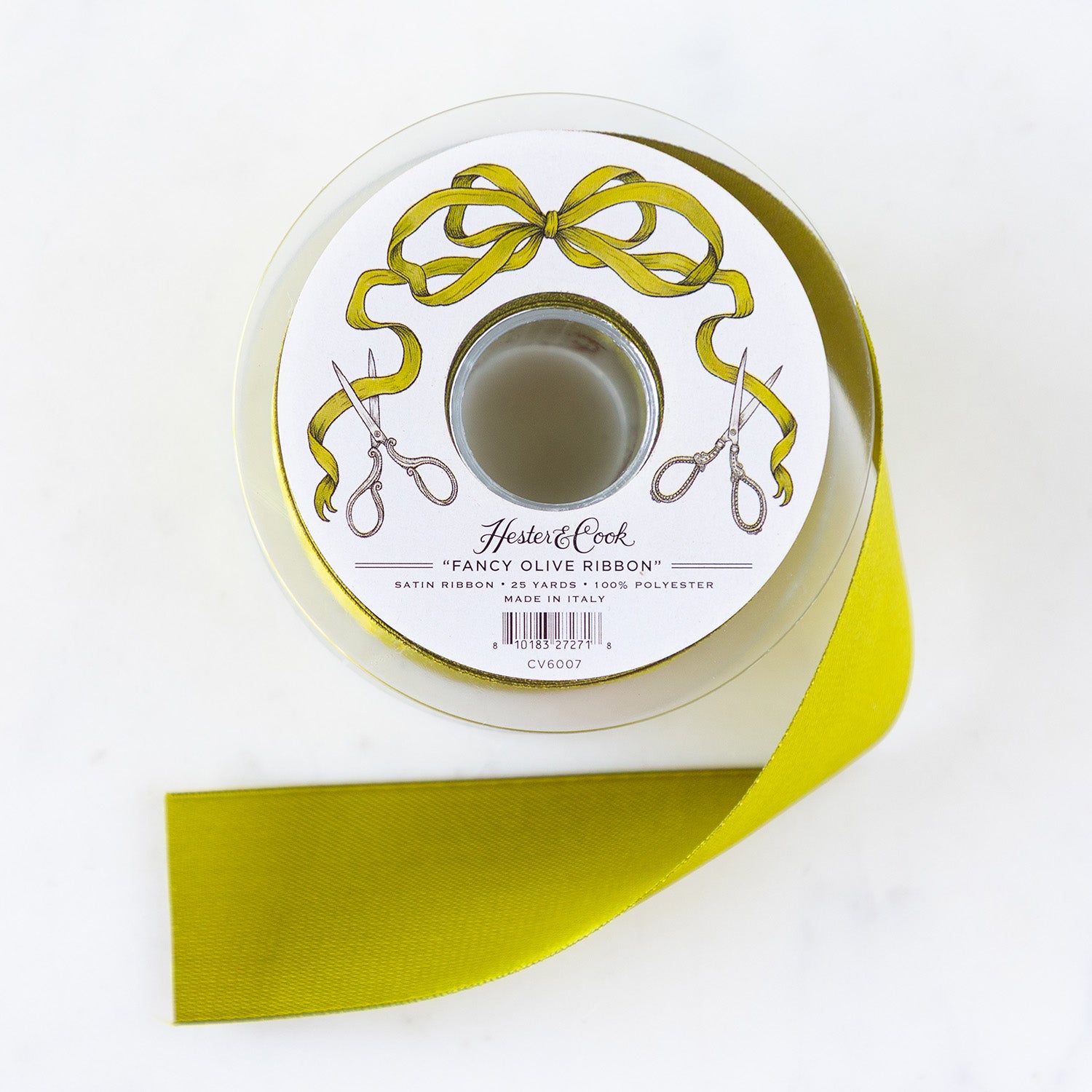 A spool of olive-green satin ribbon with a label featuring illustrated scissors and olive bow branded "Hester & Cook Fancy Olive Ribbon.