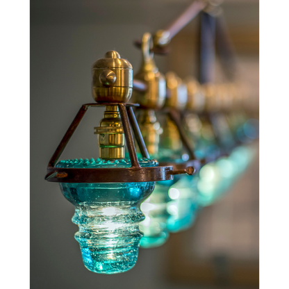 A Telegraph Pendant Lighting with four glass shades and antique insulators hanging from a brass frame. (Brand Name: Hester &amp; Cook)