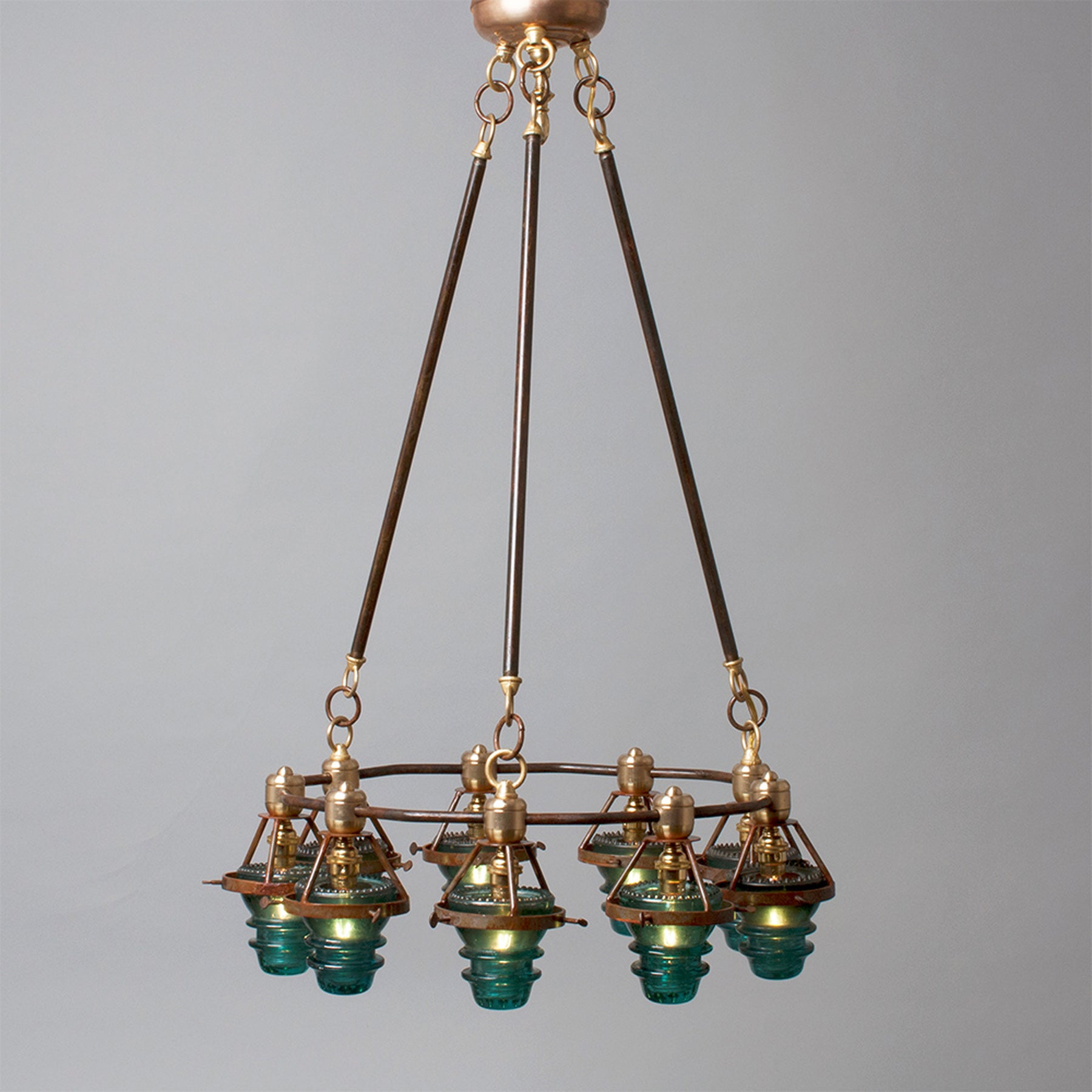 Antique bronze chandelier with multiple glass lampshades and antique insulators suspended from the ceiling, made in the USA by Hester & Cook&