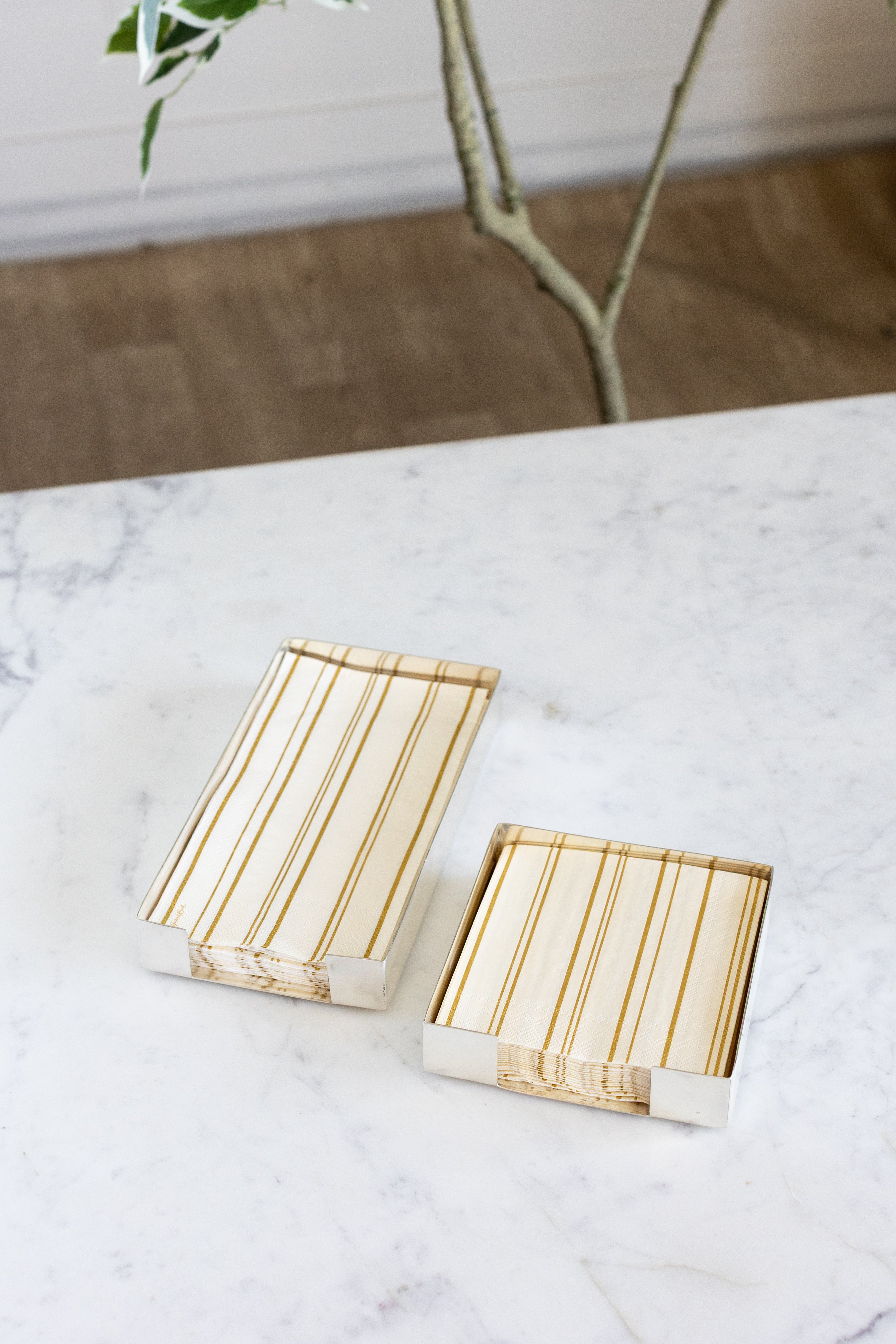 Two Silver Napkin Holders, guest-sized and cocktail-sized, containing napkins on a white table.