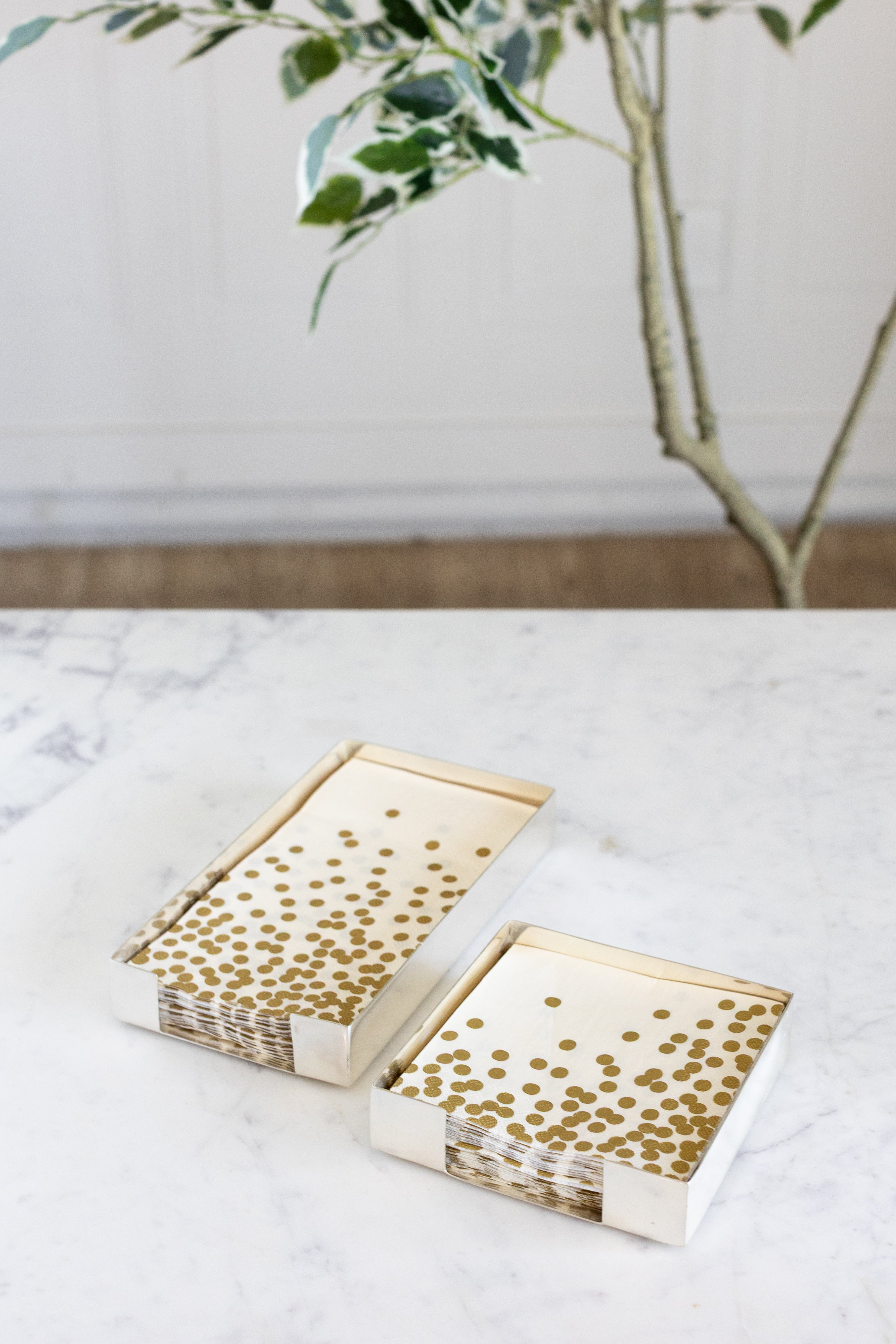 Two Silver Napkin Holders, guest-sized and cocktail-sized, containing napkins on a white table.