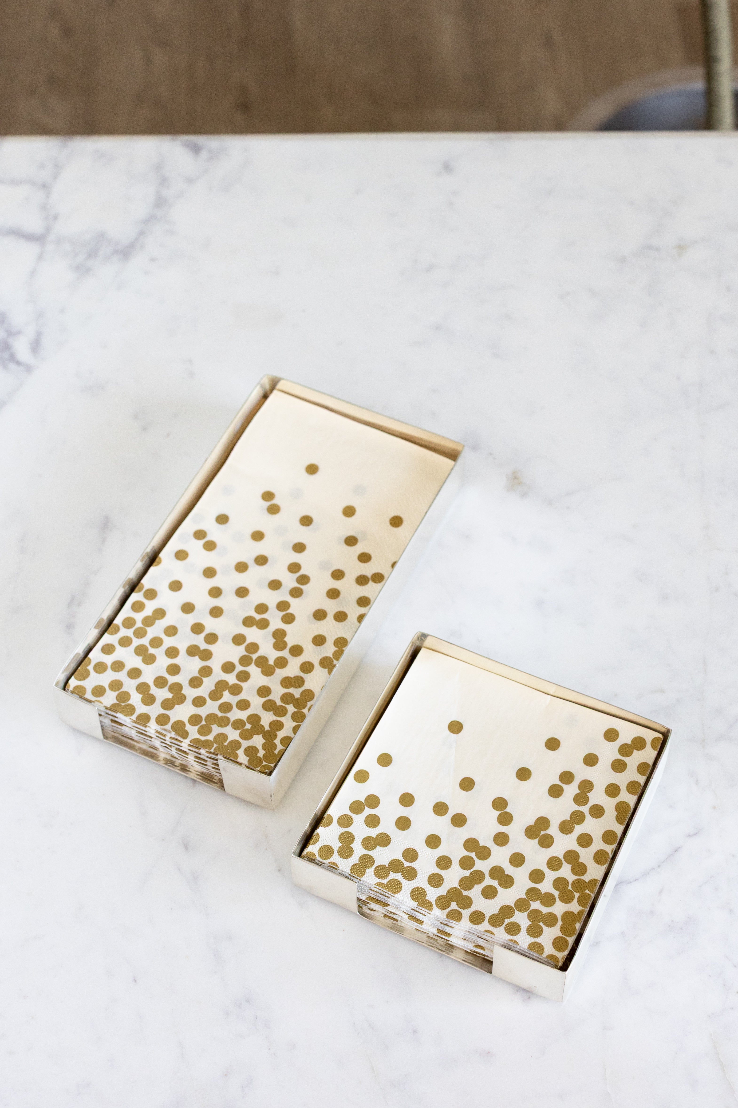 Two Silver Napkin Holders, guest-sized and cocktail-sized, containing napkins on a white table.