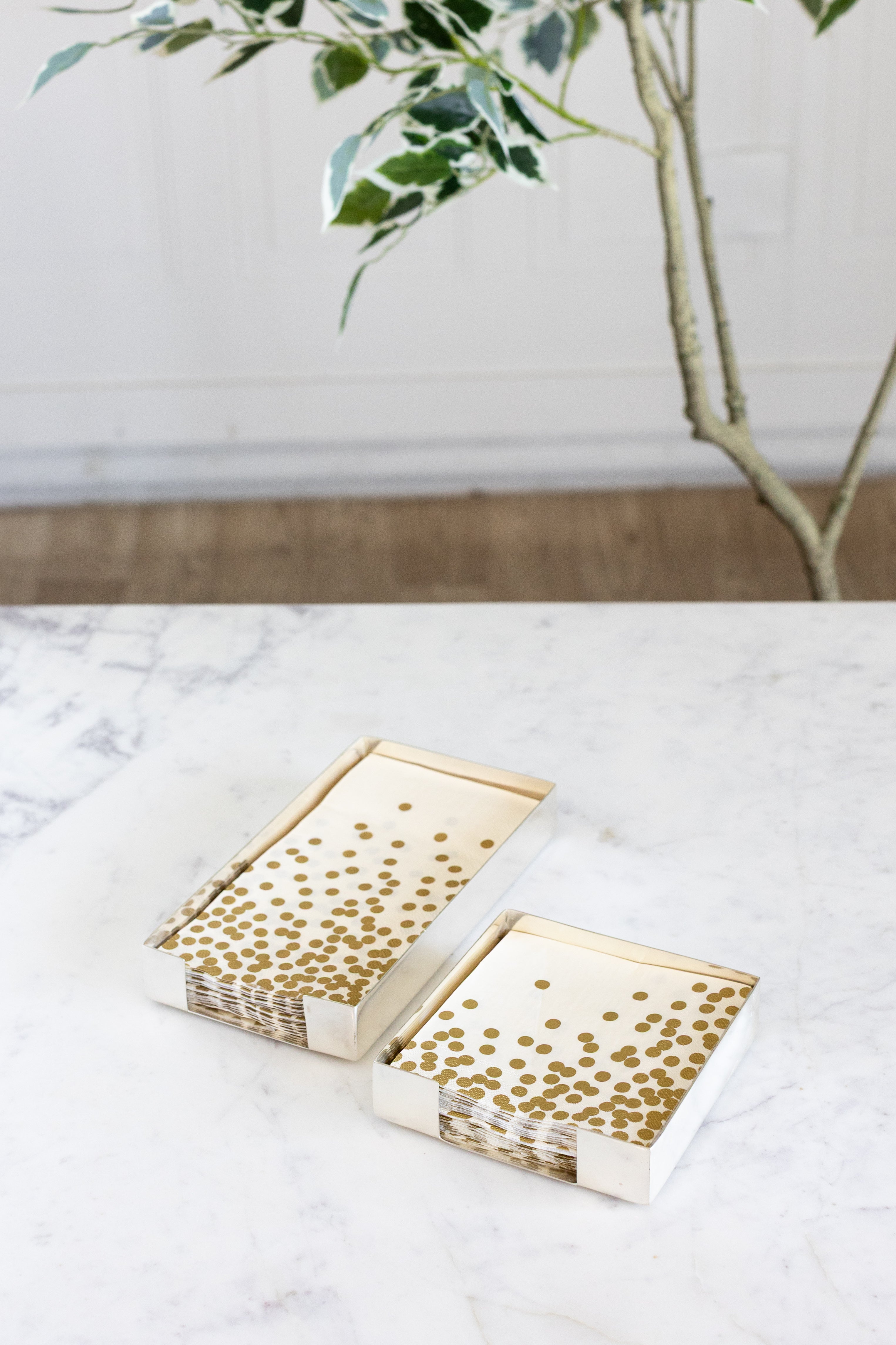 Two Silver Napkin Holders, guest-sized and cocktail-sized, containing napkins on a white table.