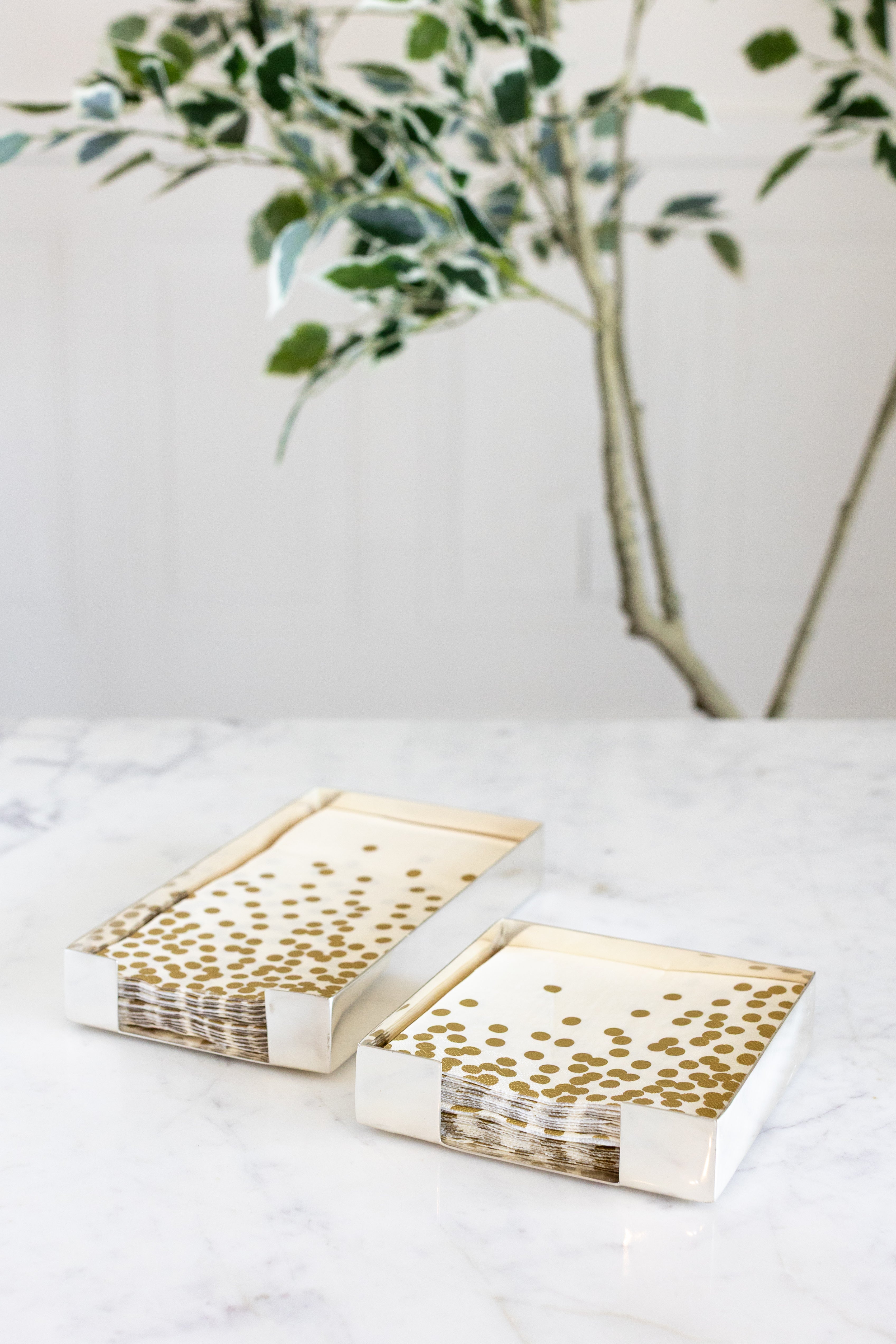 Two Silver Napkin Holders, guest-sized and cocktail-sized, containing napkins on a white table.