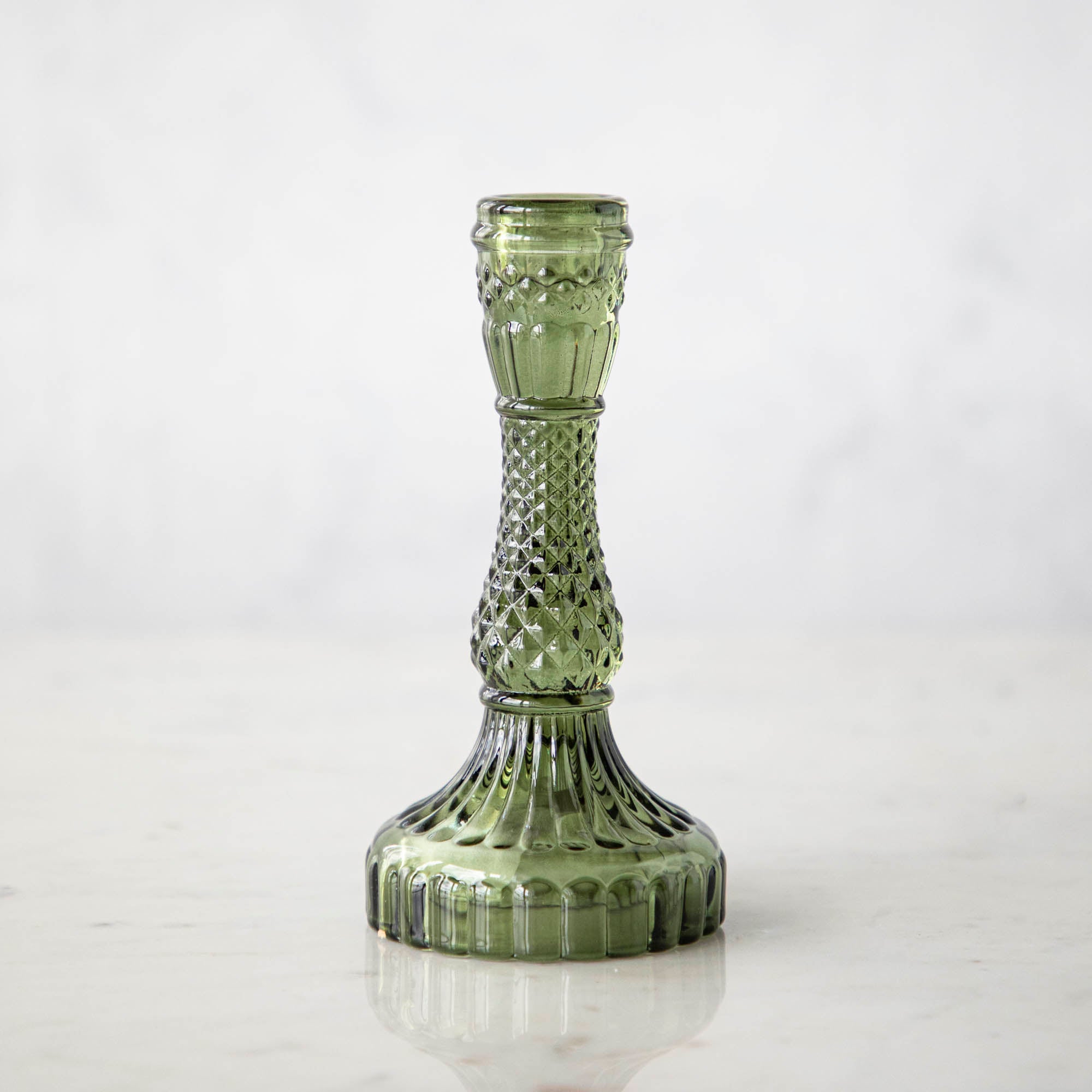 A vintage green glass candlestick on a light background.