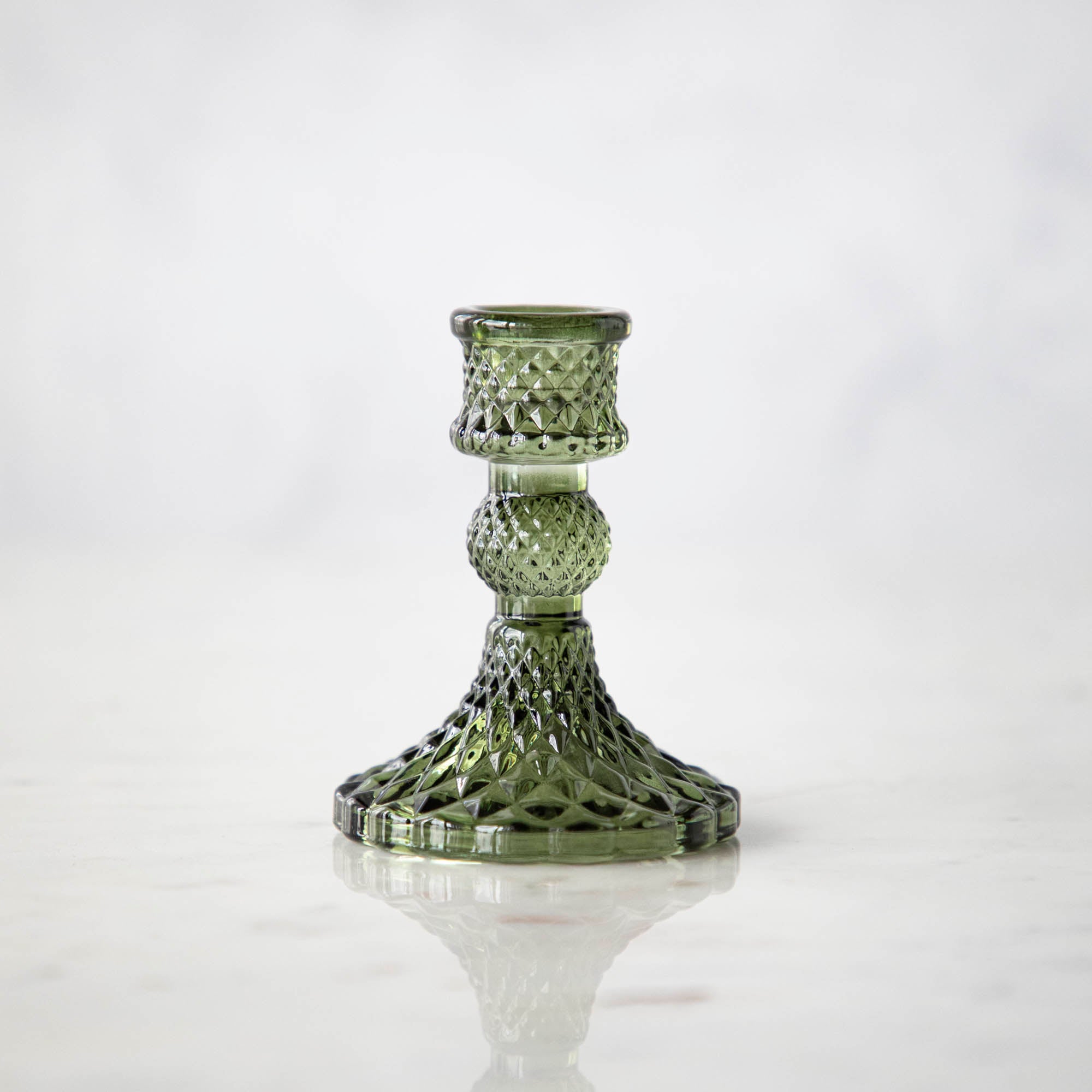 A vintage green glass candlestick on a light background.