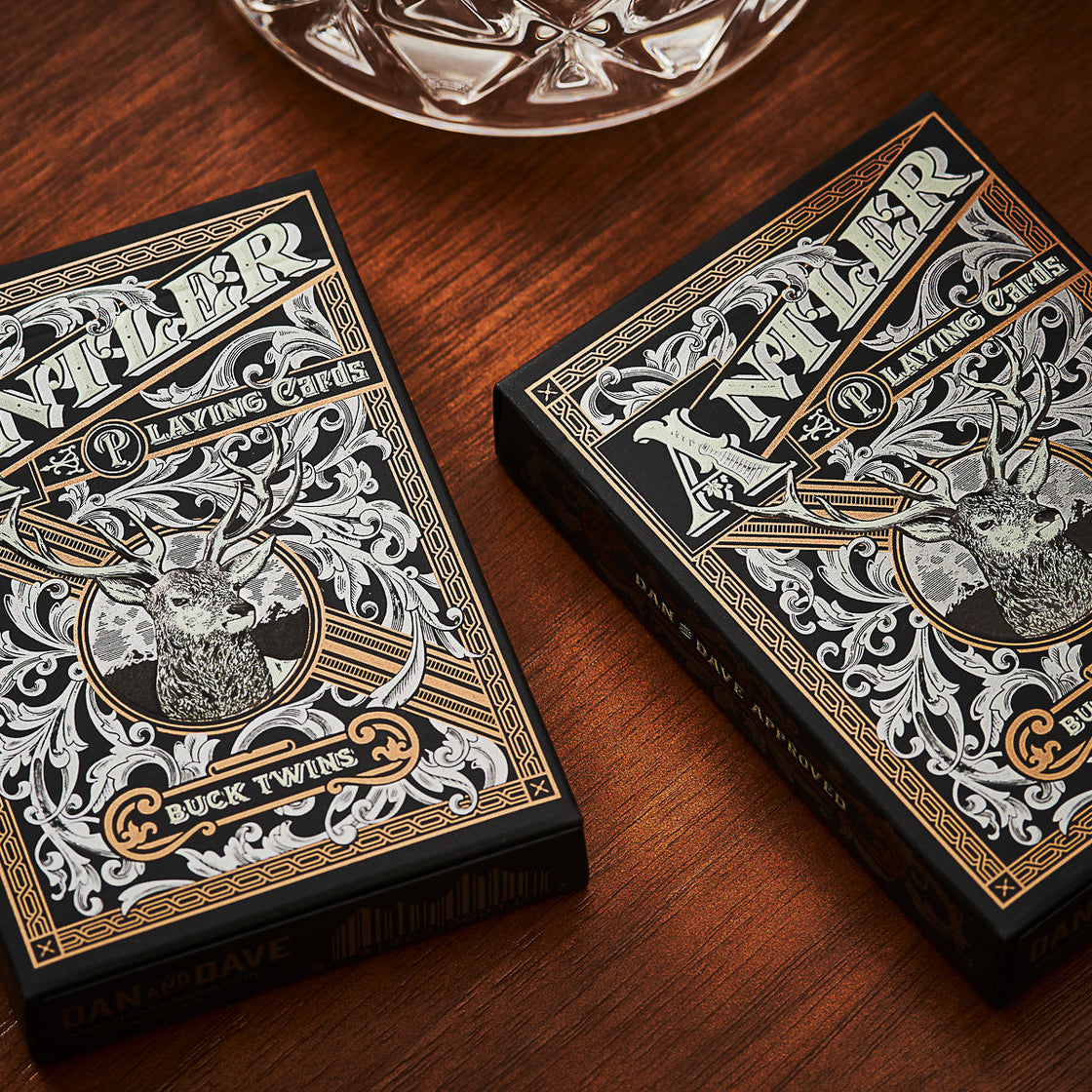 Two decks of Antler Buck Twins playing cards on a wooden surface.
