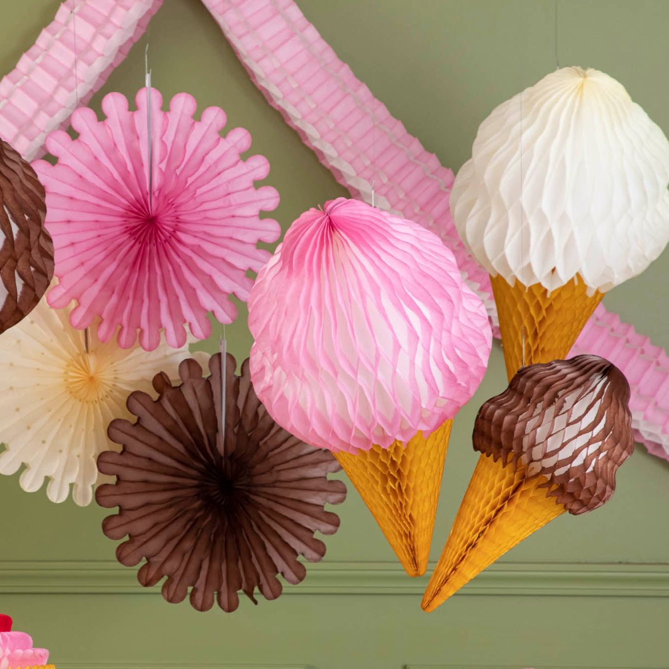 Honeycomb Celebration Garland strung on a wall amongst giant honeycomb ice cream cones and giant honeycomb fans.
