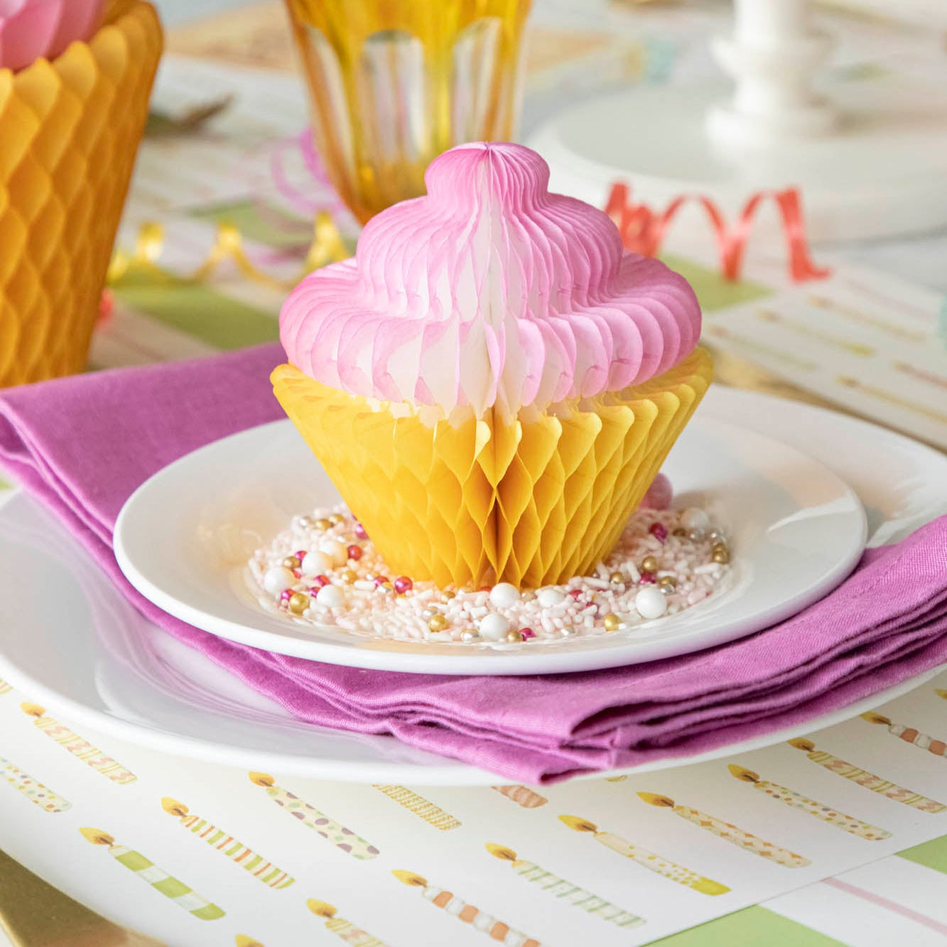 Honeycomb Medium Cupcake on top of a plate surrounded by sprinkles, on a fun, birthday themed table setting.