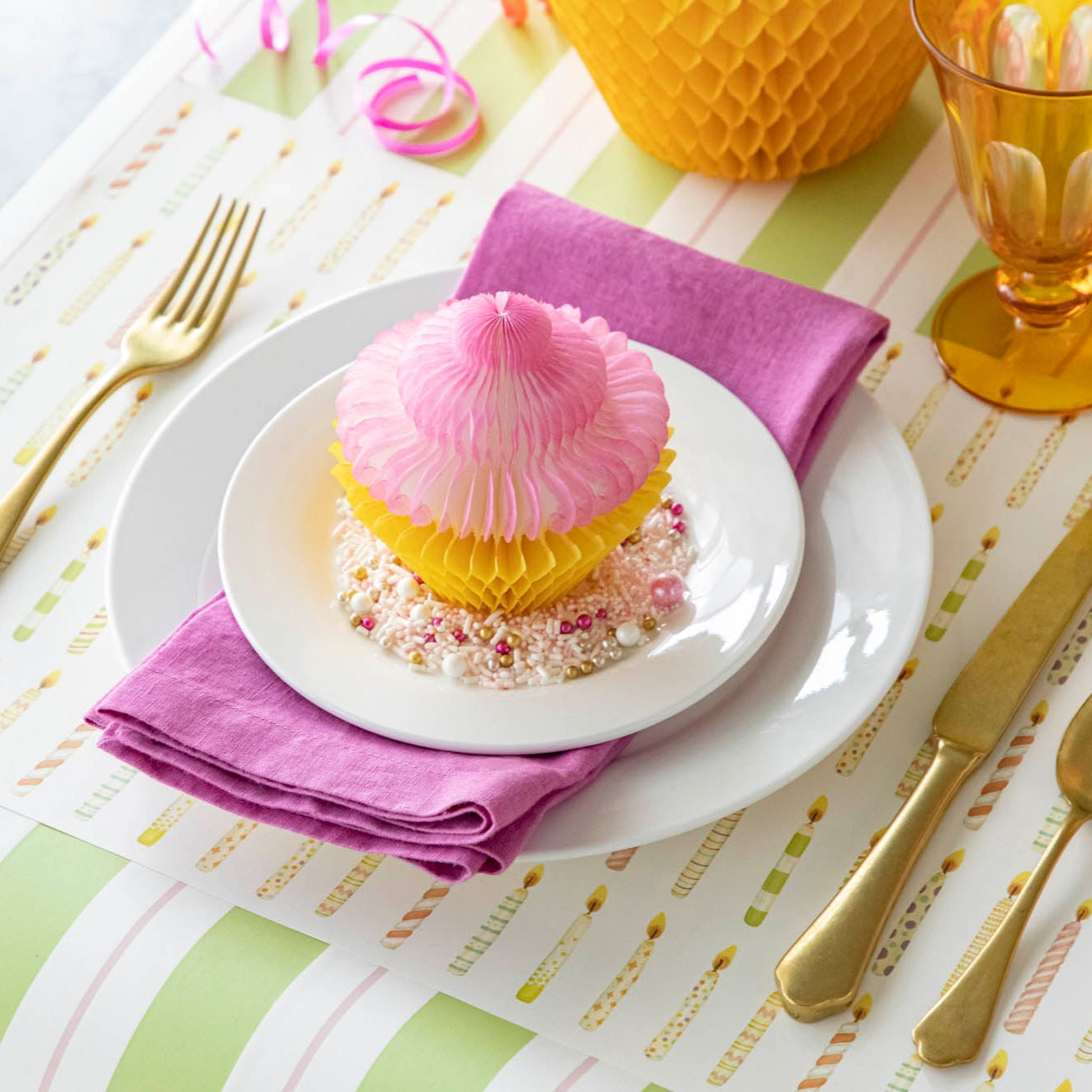 Honeycomb Medium Cupcake on top of a plate surrounded by sprinkles, styled on a fun, birthday themed table setting.