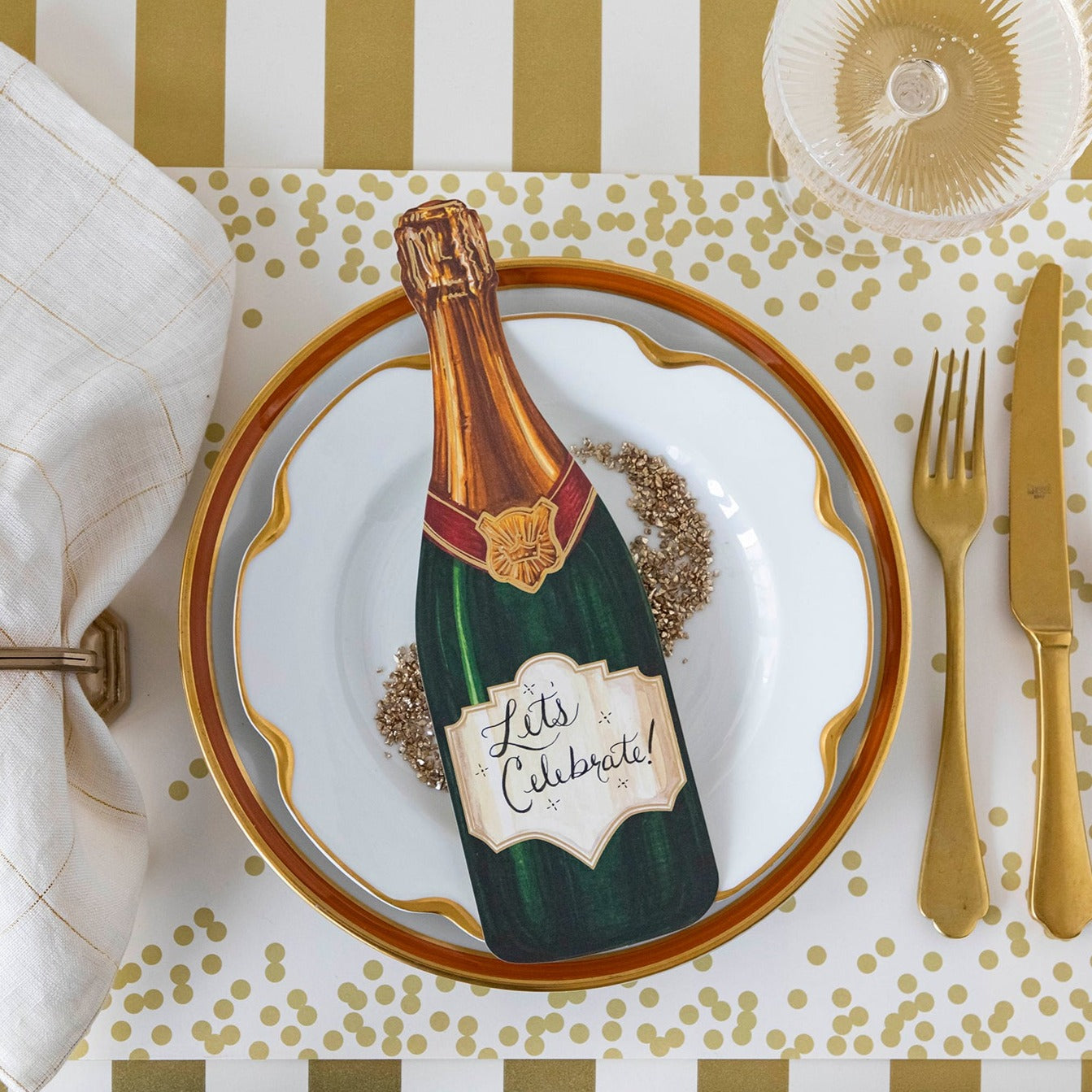 Top-down view of an elegant place setting featuring a Champagne Table Accent with "Let&