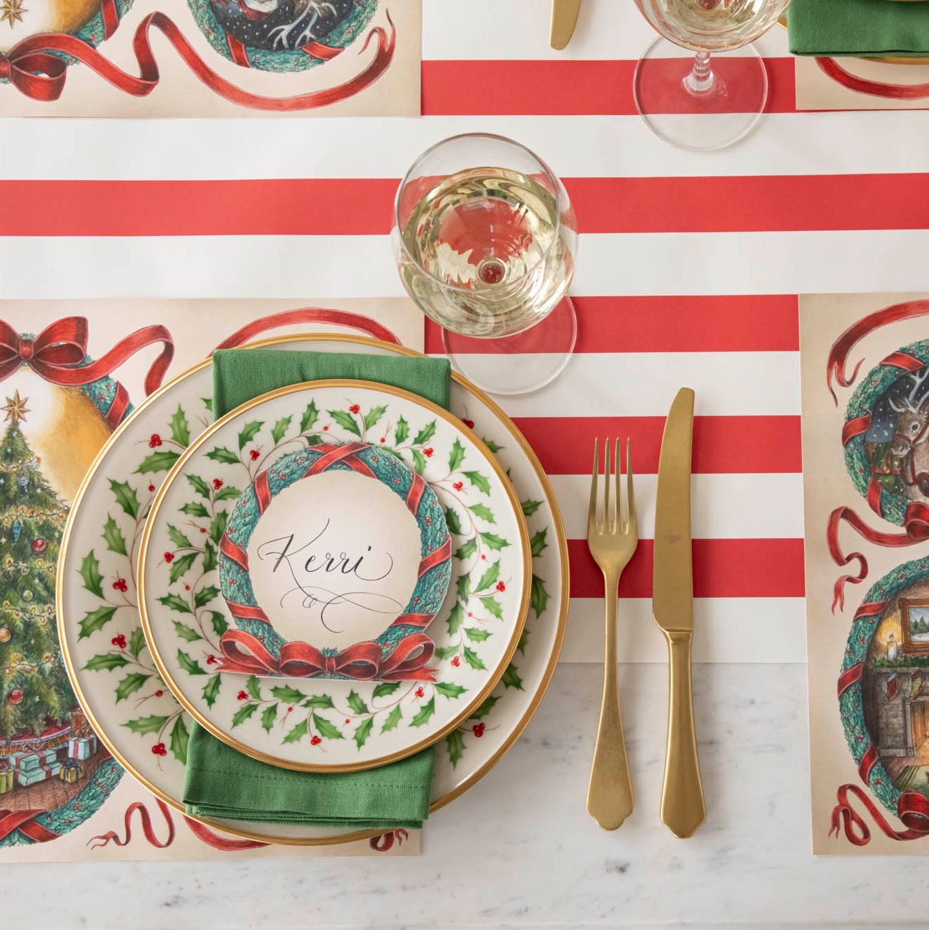 An elegant Christmas themed table setting with the Red Classic Stripe Runner underneath holly rimmed plates and O Christmas Tree Wreath Place Card with the name "Kerri" written on it.