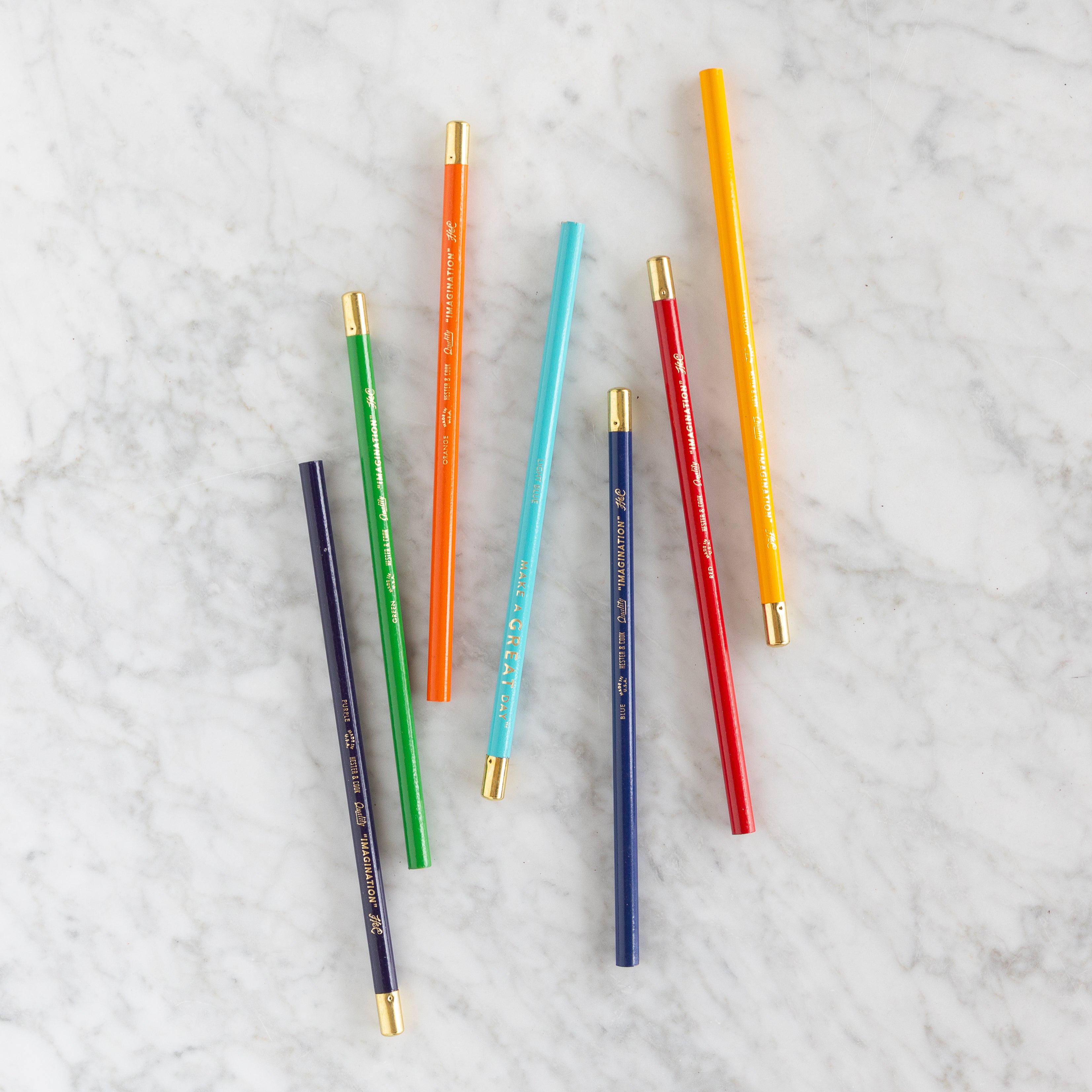 Set of colorful pencils with gold accents on a light gray background.