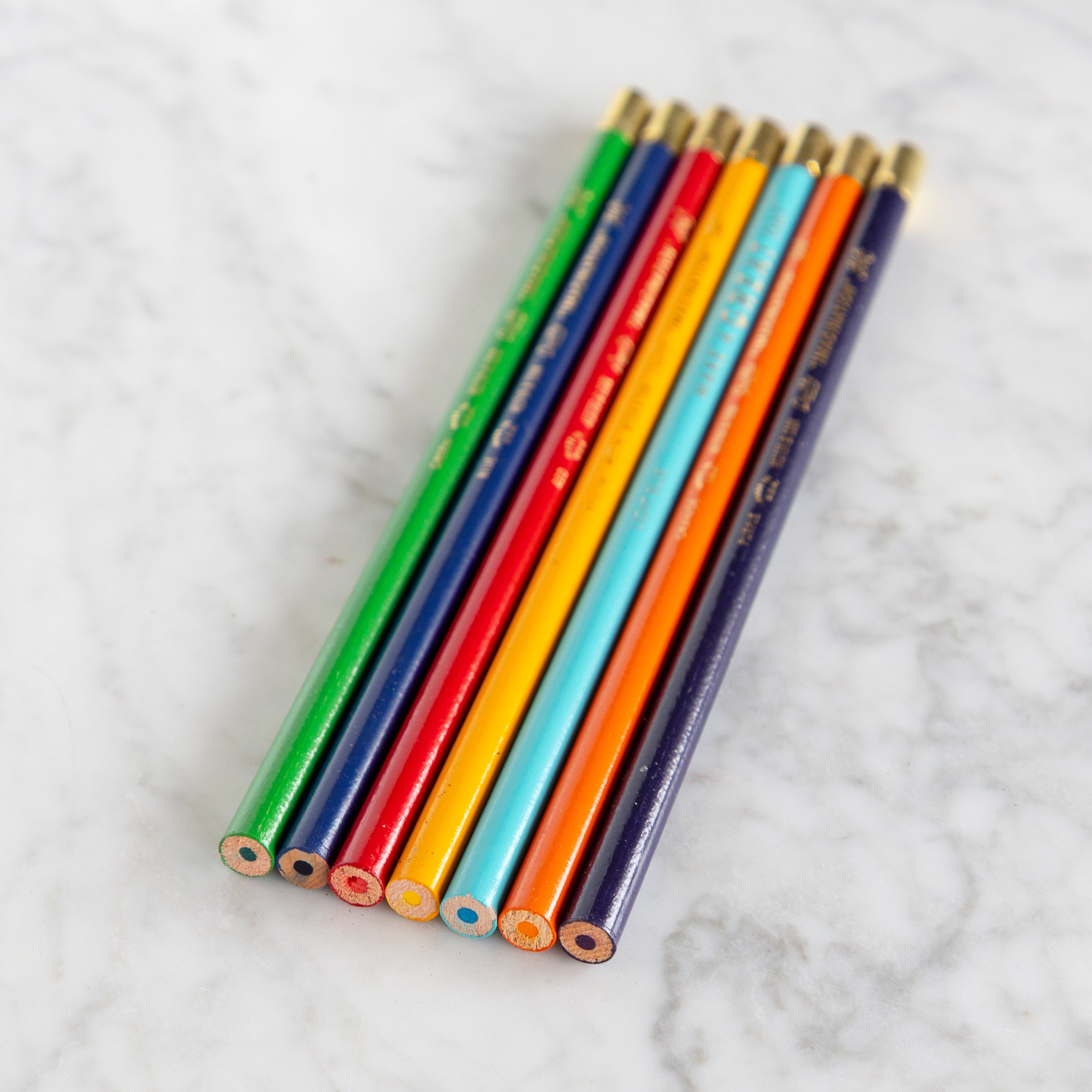 Set of colorful pencils on a marble surface.