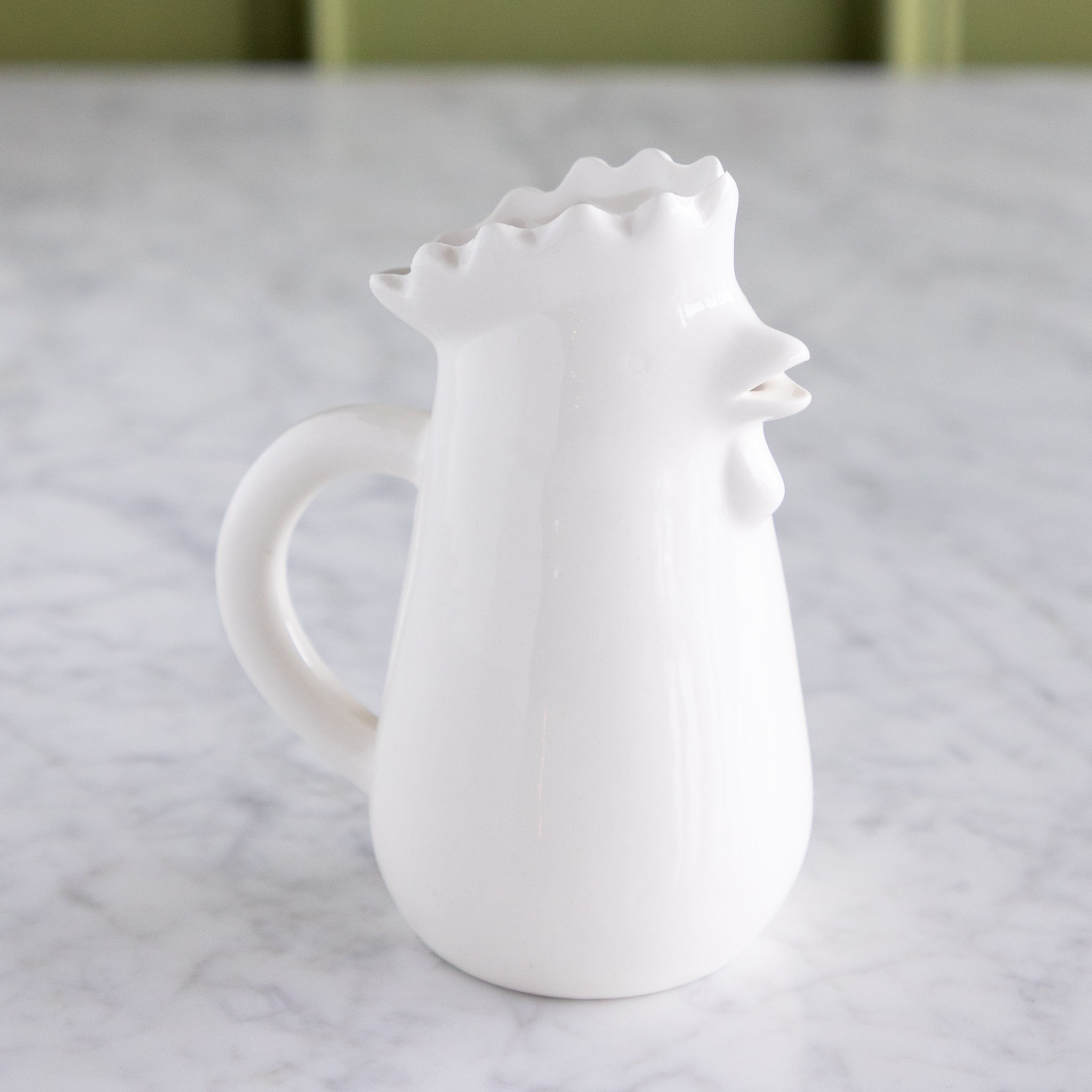 Stoneware Chicken Creamer on a marble table.