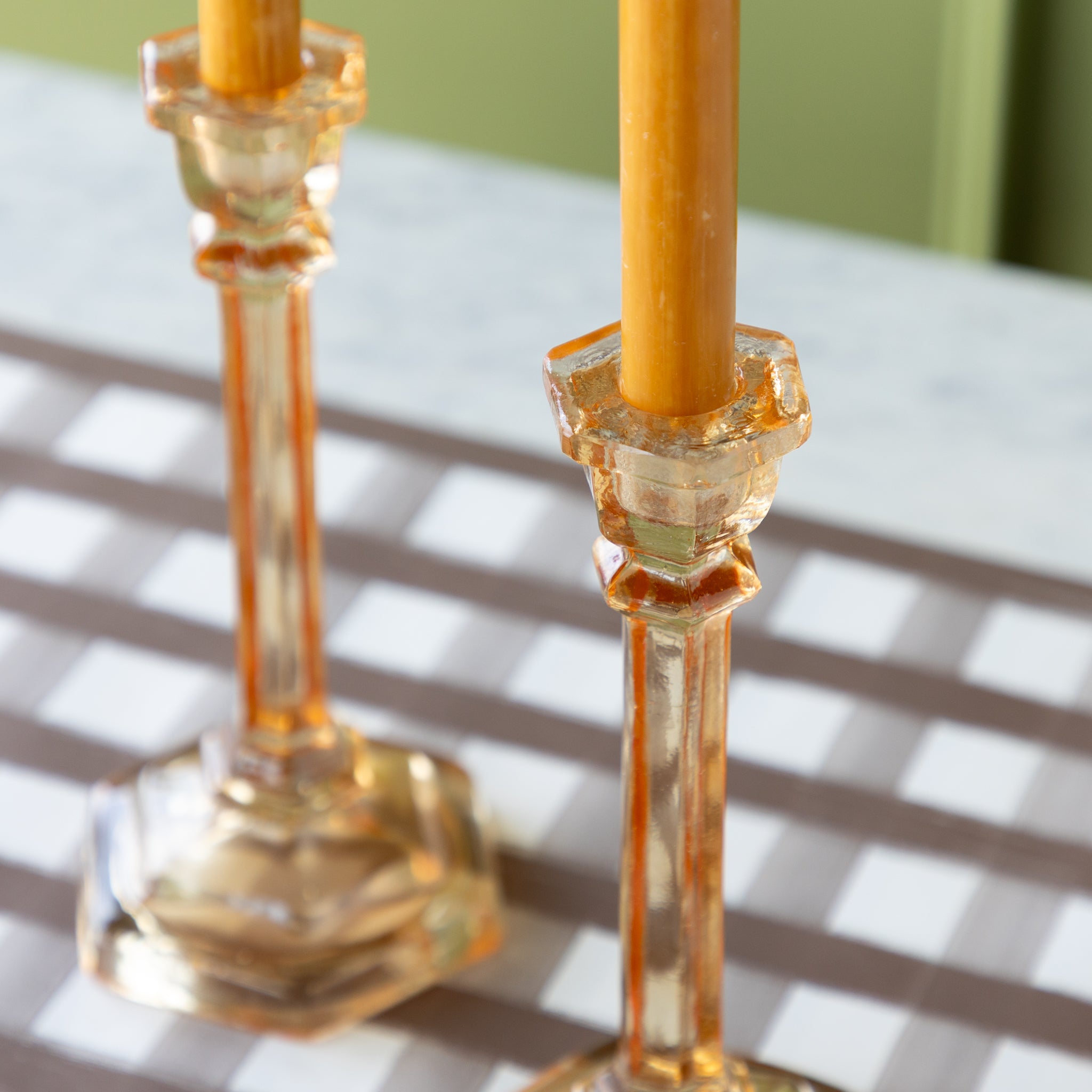 Two amber-colored candles in Amber Glass Candle Holders.