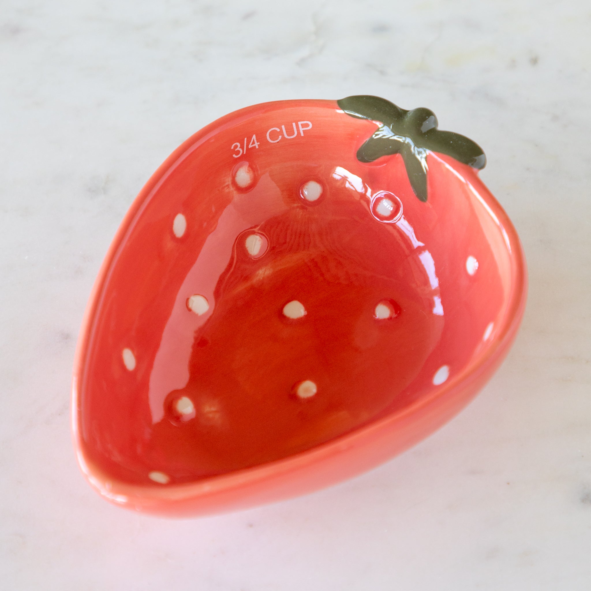 Red ceramic measuring cup shaped like a strawberry with &