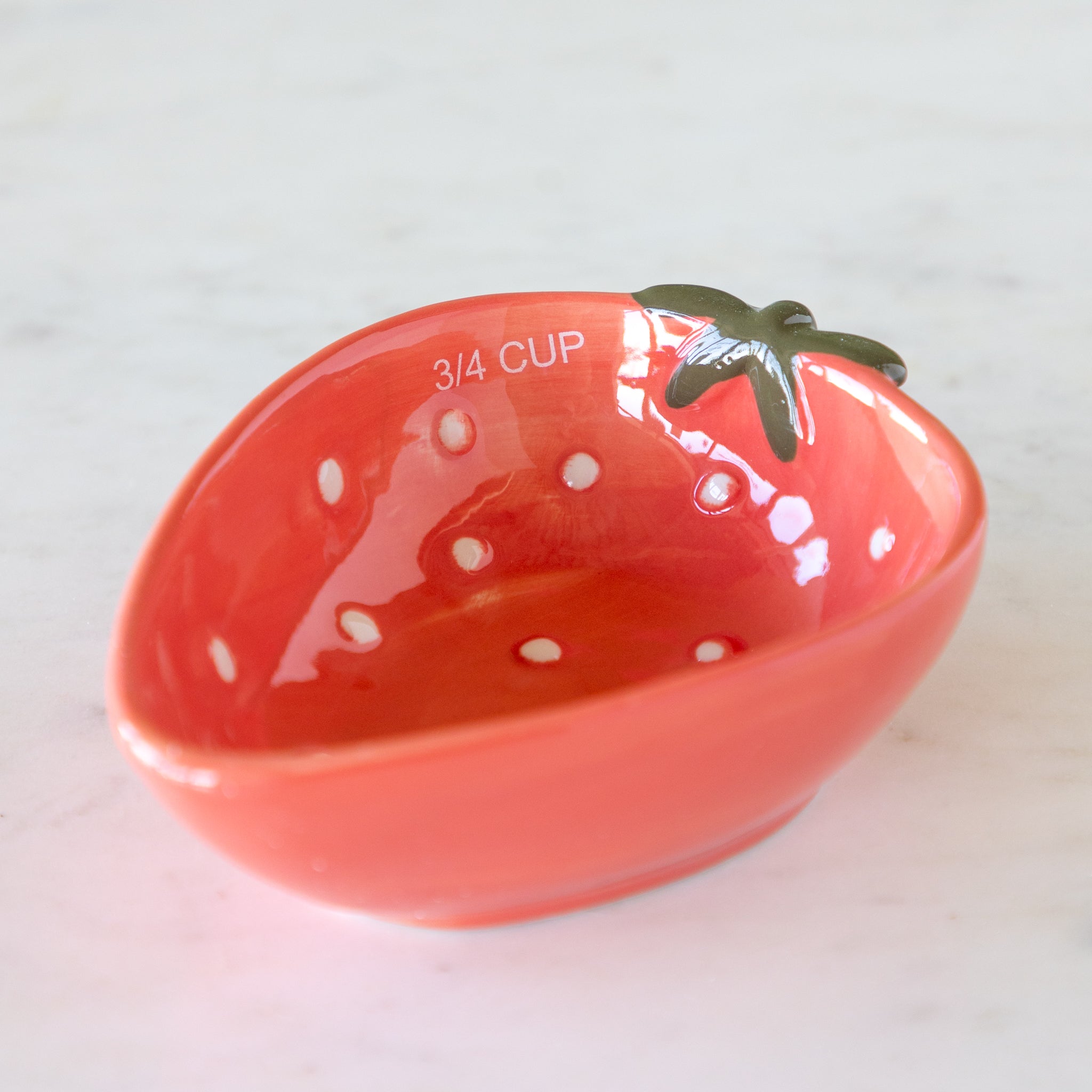 Red ceramic measuring cup shaped like a strawberry with &