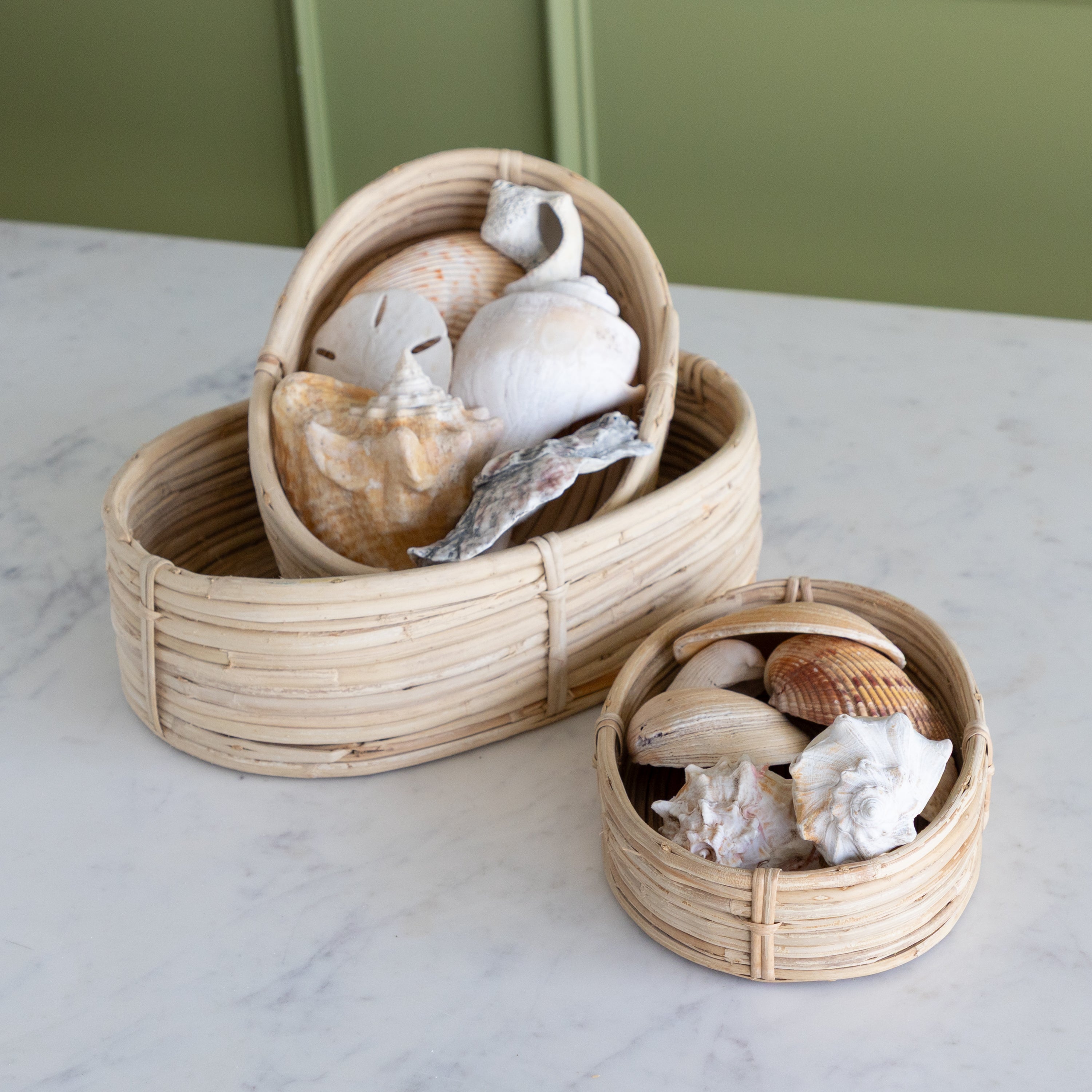 Two woven baskets with seashells on a marble surface